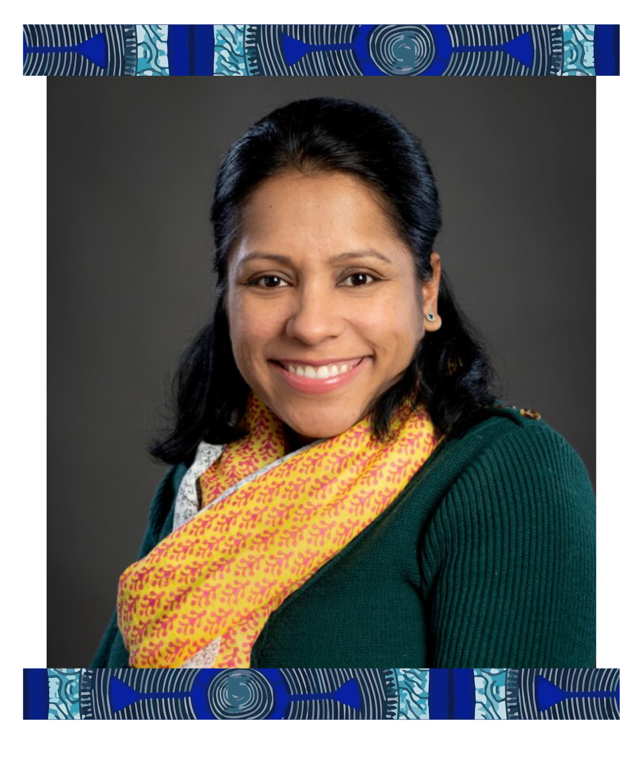 A woman with dark hair smiling, wearing a teal sweater and a yellow and pink patterned scarf against a gray background.