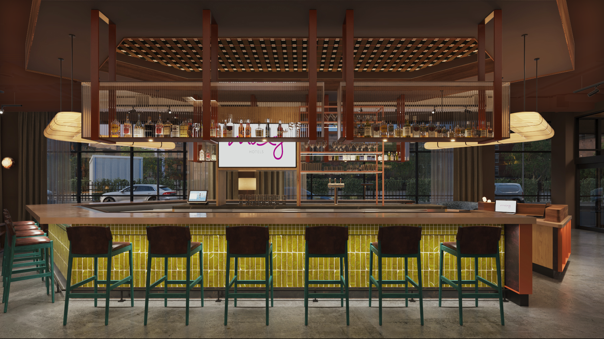 Modern hotel bar with a yellow-tiled counter, green chairs, a hanging liquor shelf, and large windows showing parked cars outside.