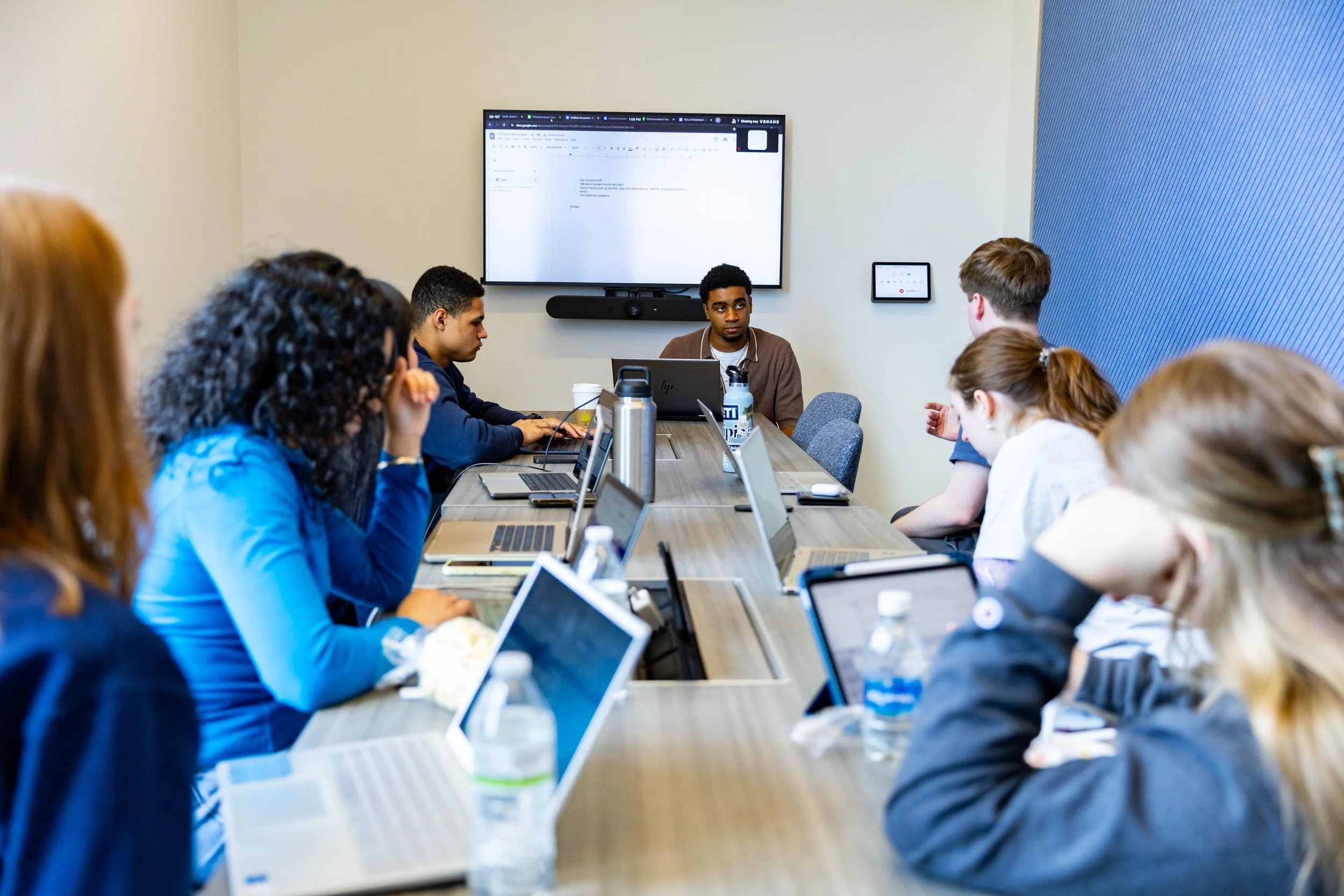 TEDxQuinnipiacU team members engaging in conversation around a conference room table