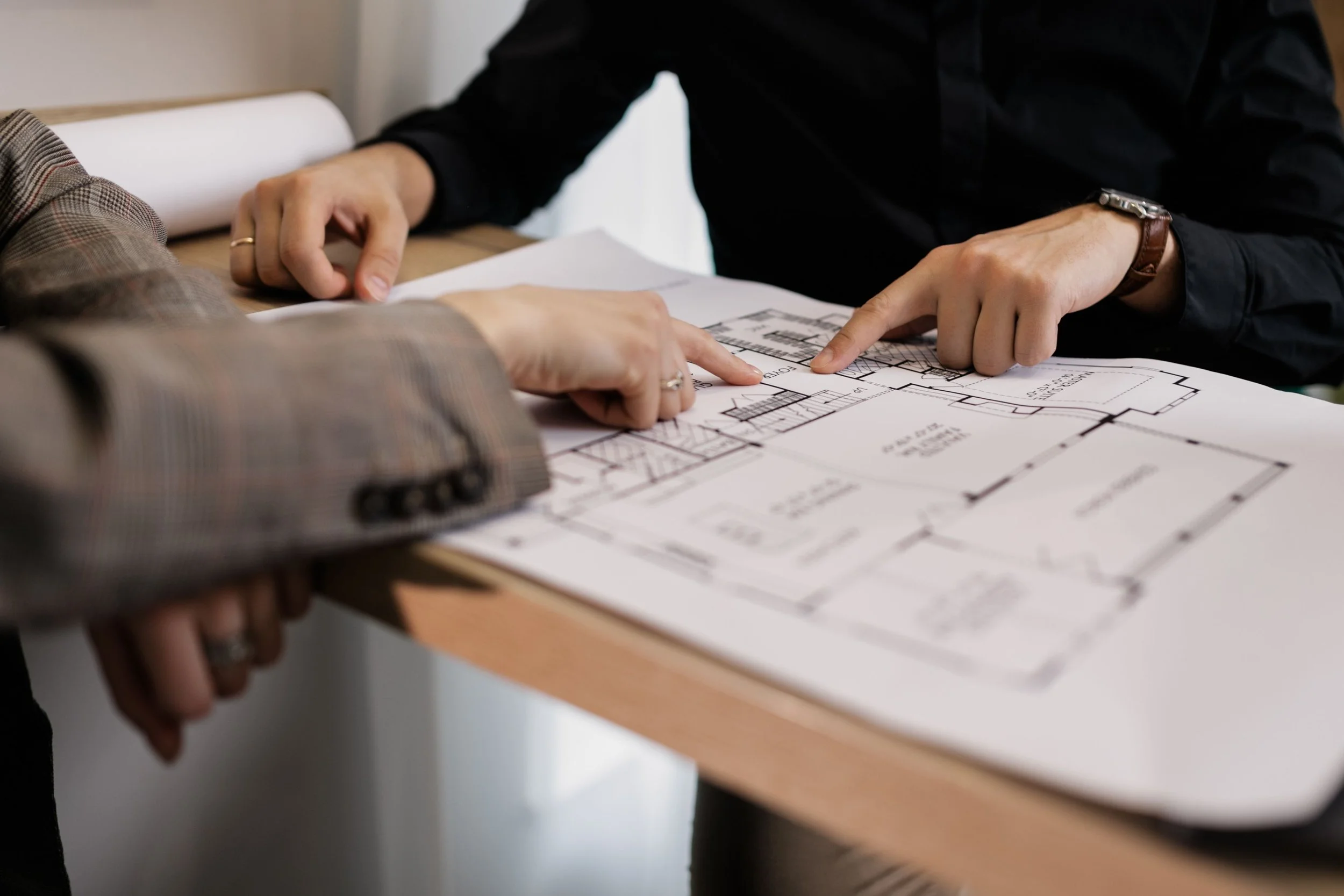 People reviewing architectural blueprints on a table.