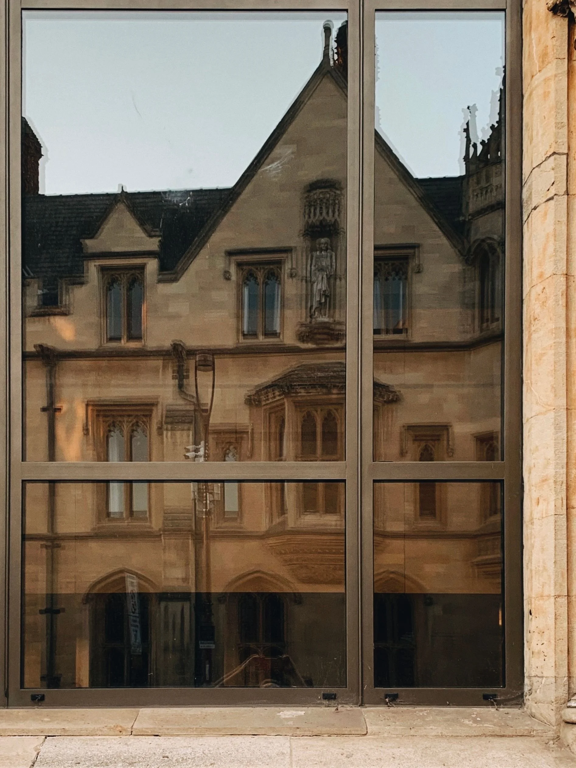 Reflection of historic building with arched windows and decorative architecture in glass door or window
