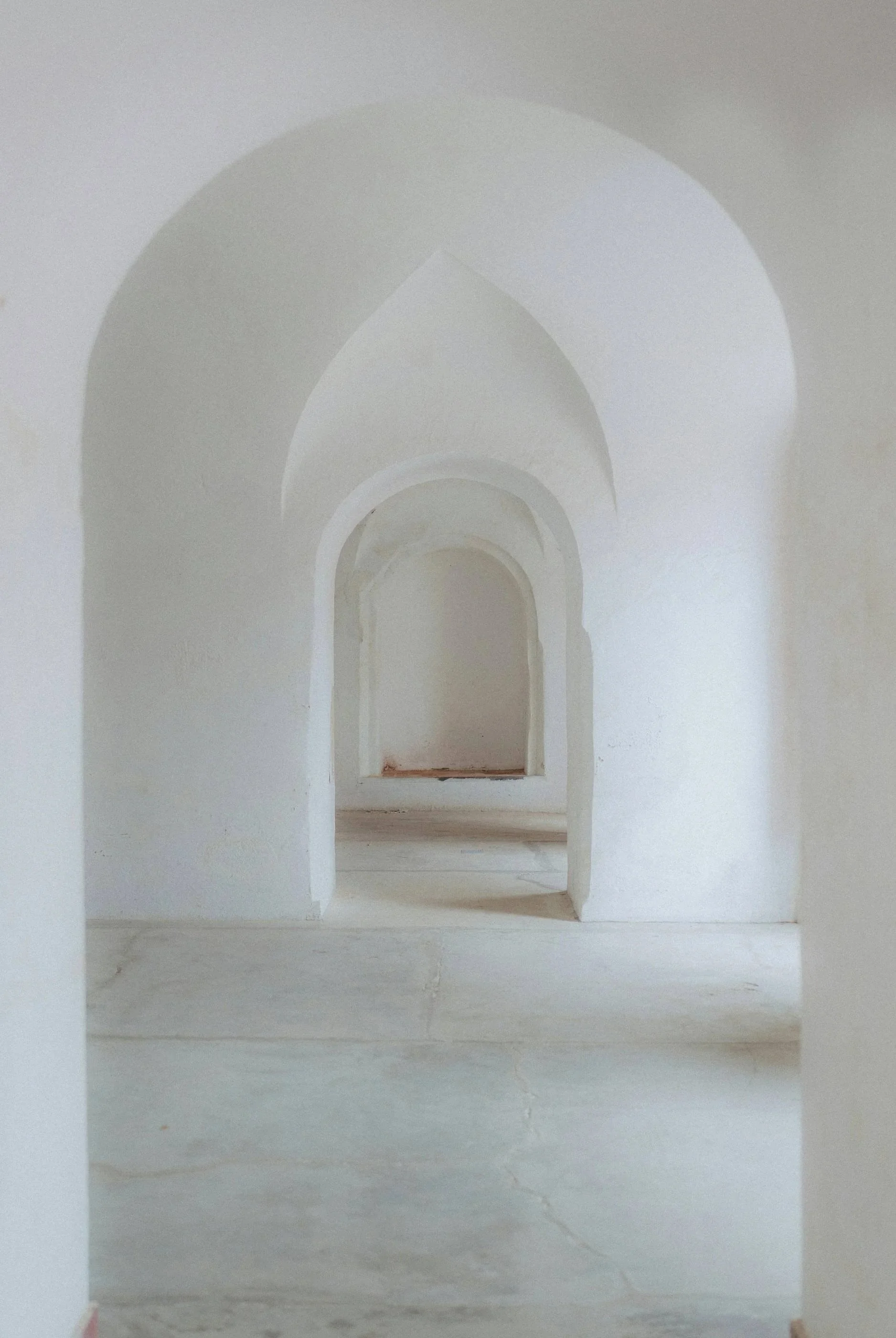 Series of arched doorways inside a white building, creating a tunnel-like perspective.