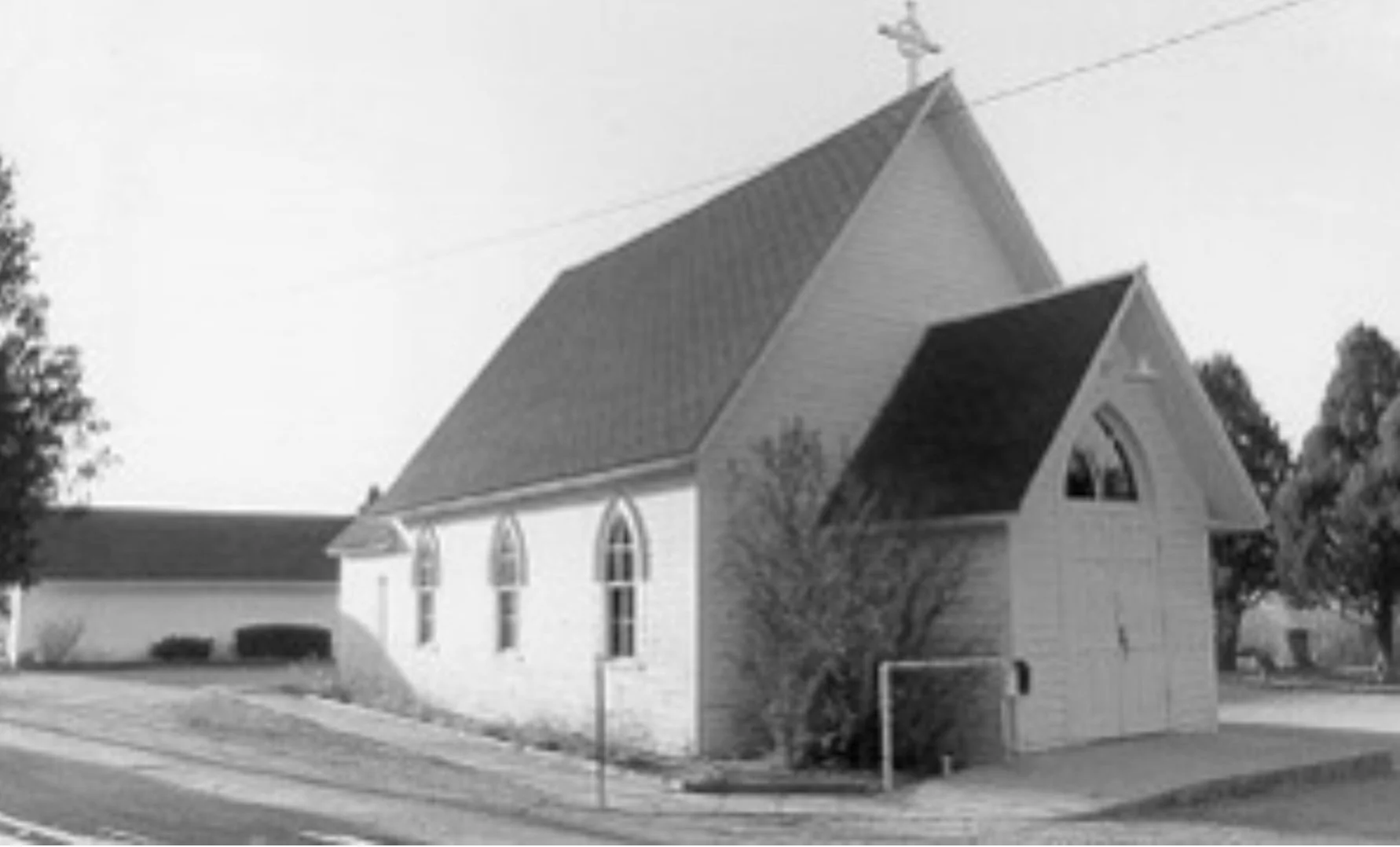 black and white photo of a church with steep roof and cross on top