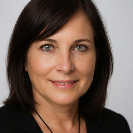 Close-up portrait of a woman with shoulder-length dark brown hair, blue eyes, and light skin, smiling gently, wearing a black blazer.