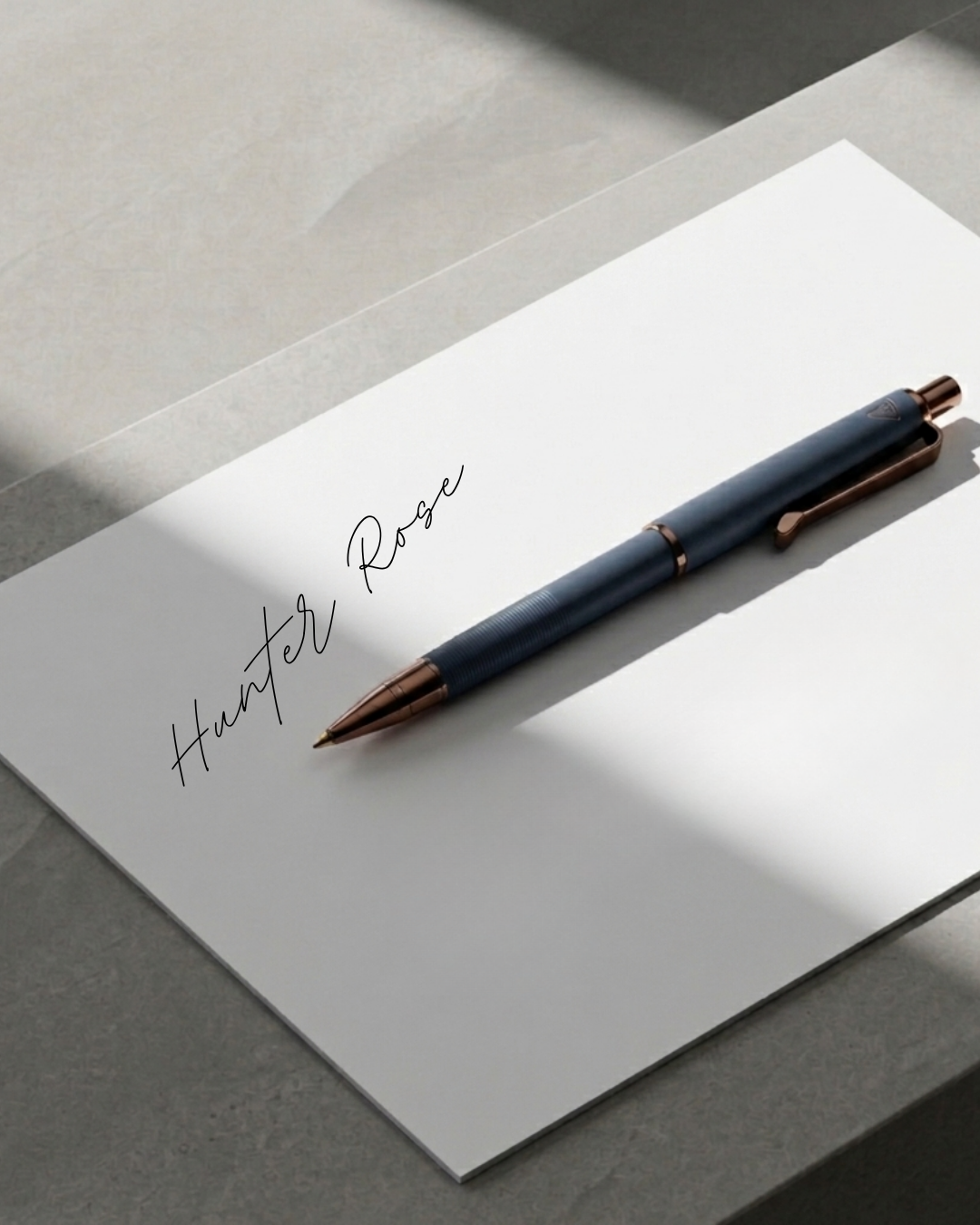 A sheet of paper with the handwritten words "Hunter Rose" and a pen resting on it.
