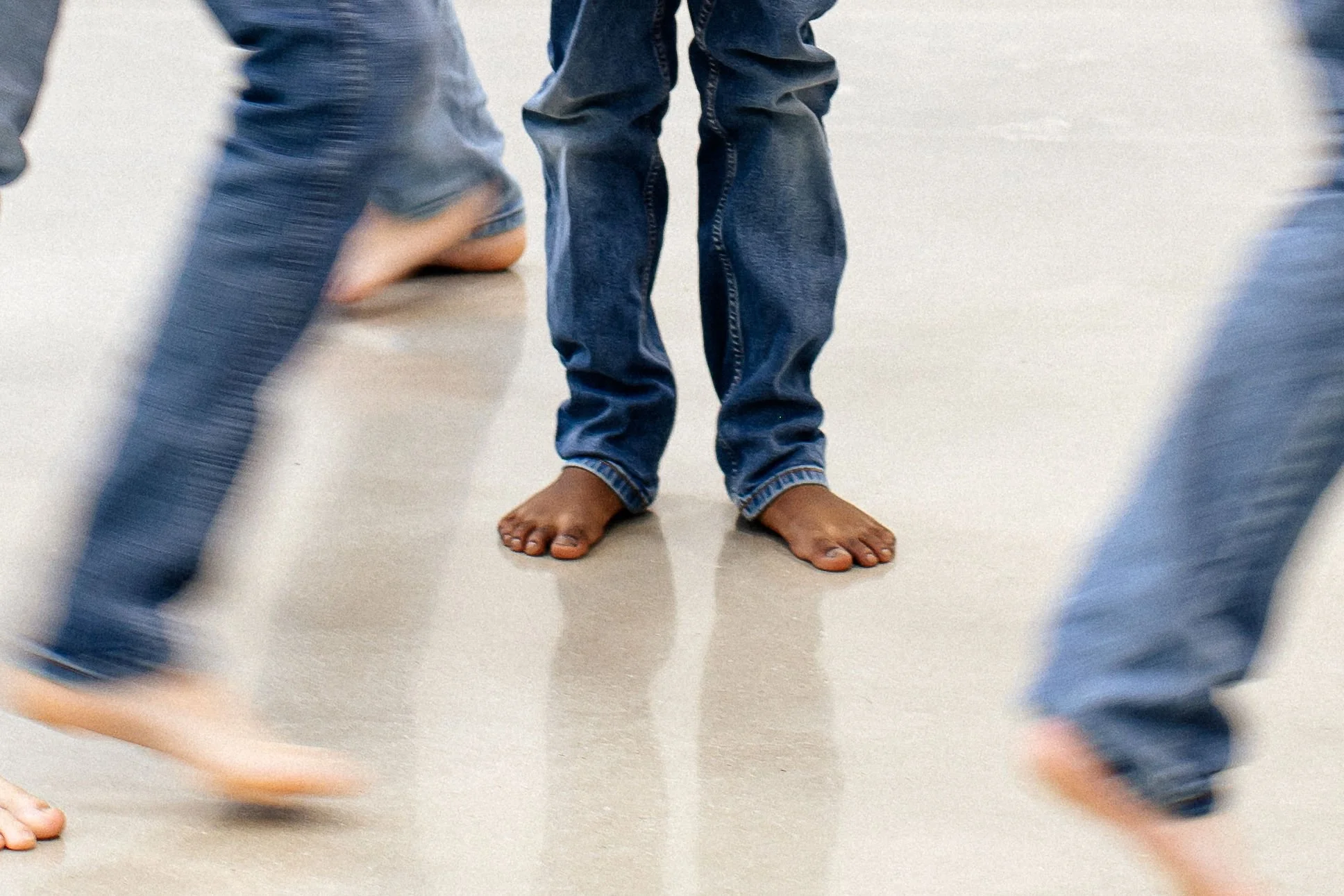 Feet of children in jeans and barefoot, running and standing on a smooth floor.