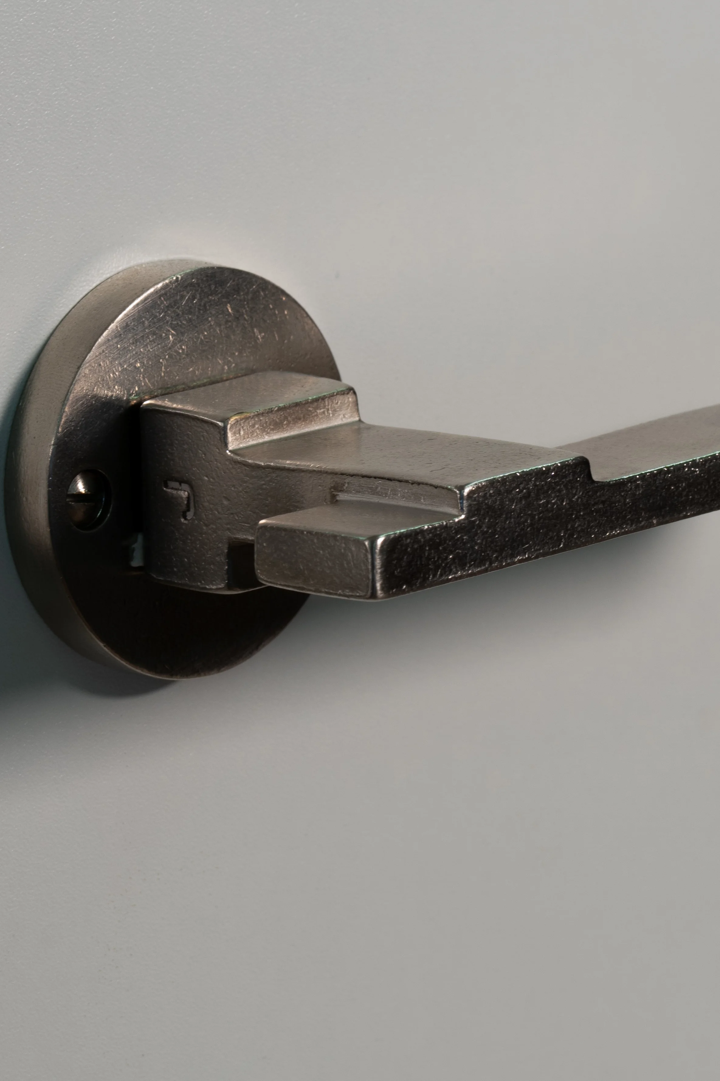 Close-up of a metal door handle installed on a light-colored door.