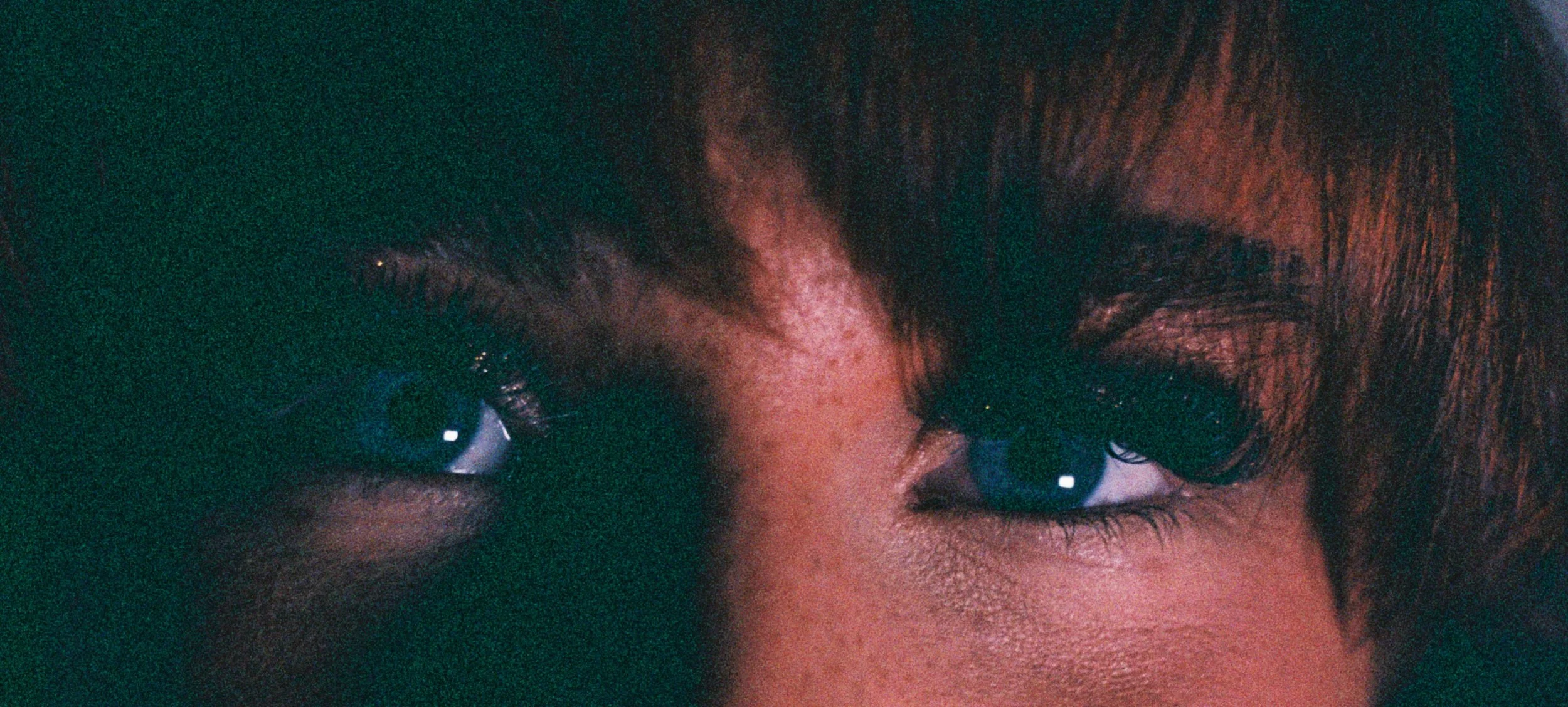 Close-up of a person's eyes with dark eyelashes and brown hair.
