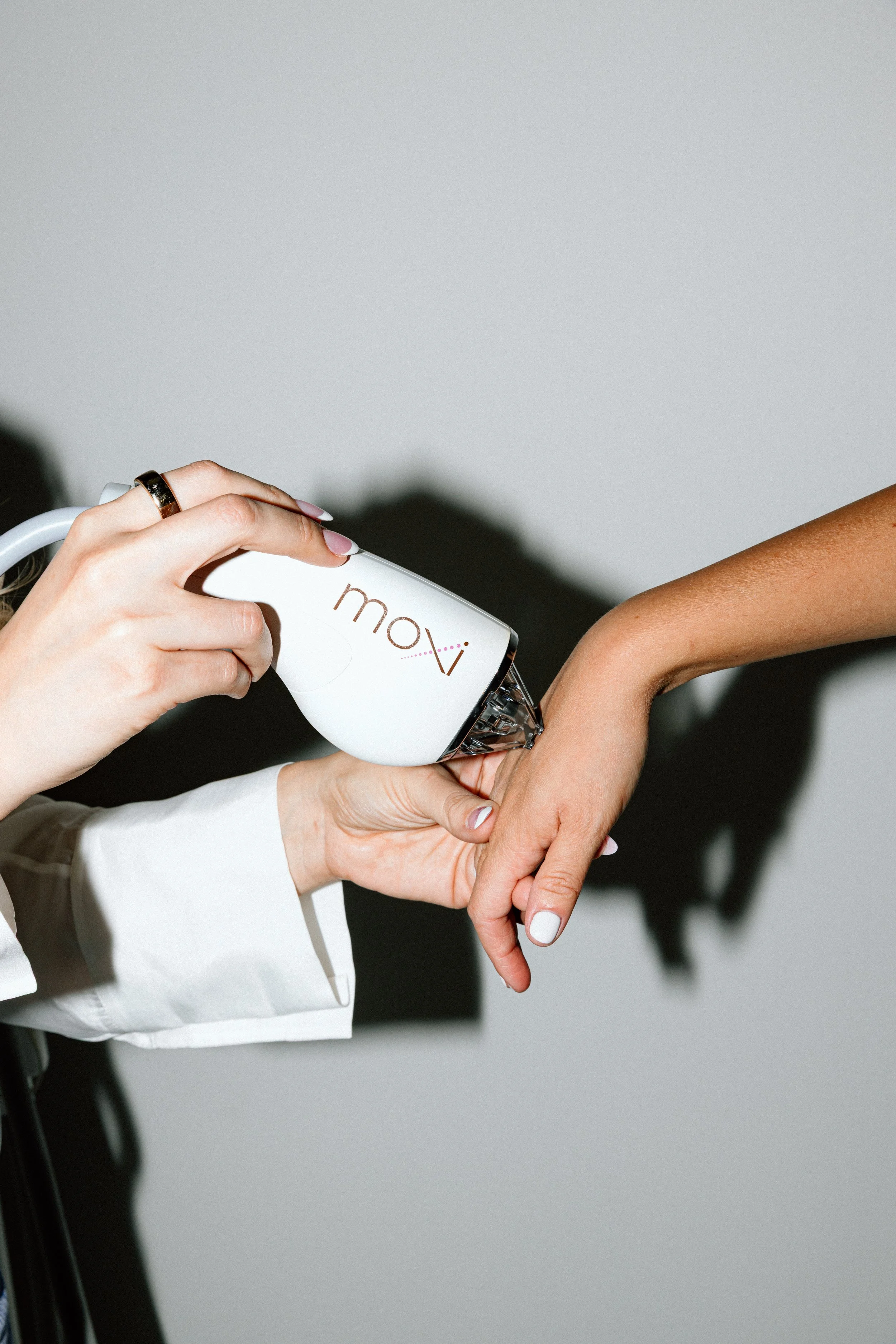 A person in a white shirt dispensing a liquid from a Moxi brand bottle onto another person's hand.