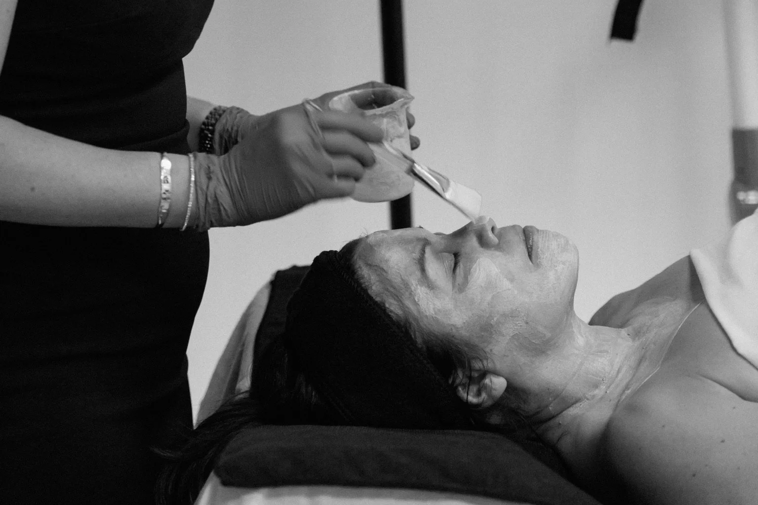 A client receiving a DMK Muscle Banding treatment with a hardened enzyme mask applied to their face and neck at a Scottsdale med spa.