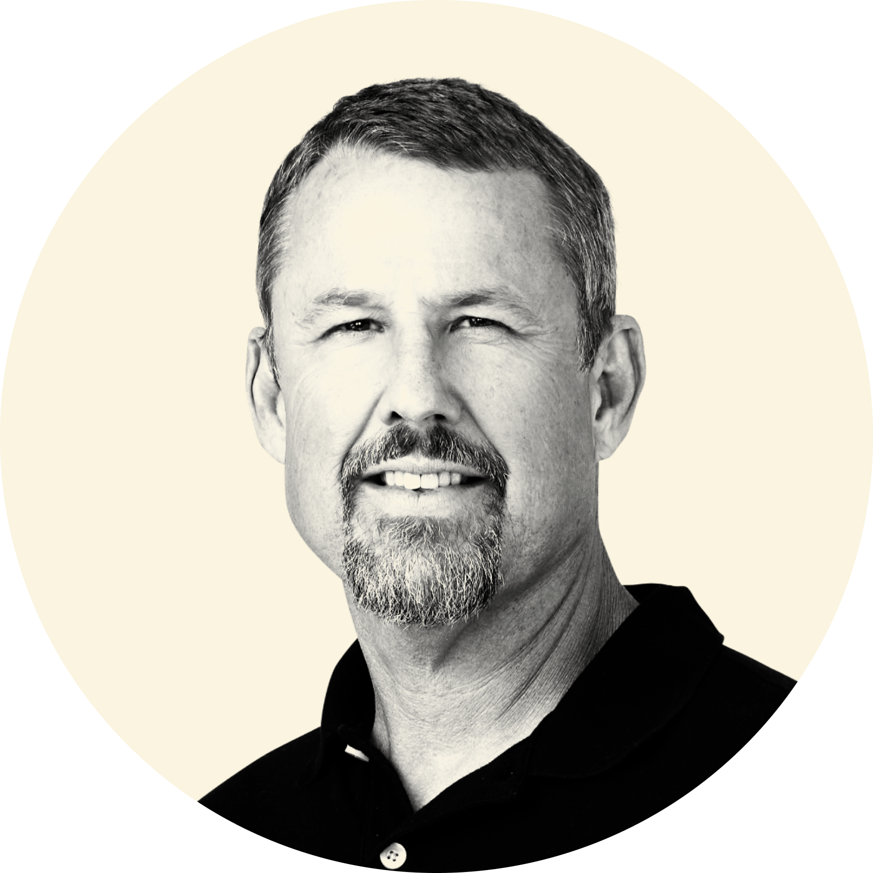 Black and white portrait of a man with short hair, a goatee, smiling, wearing a dark jacket over a shirt, against a light background with a circular graphic overlay.