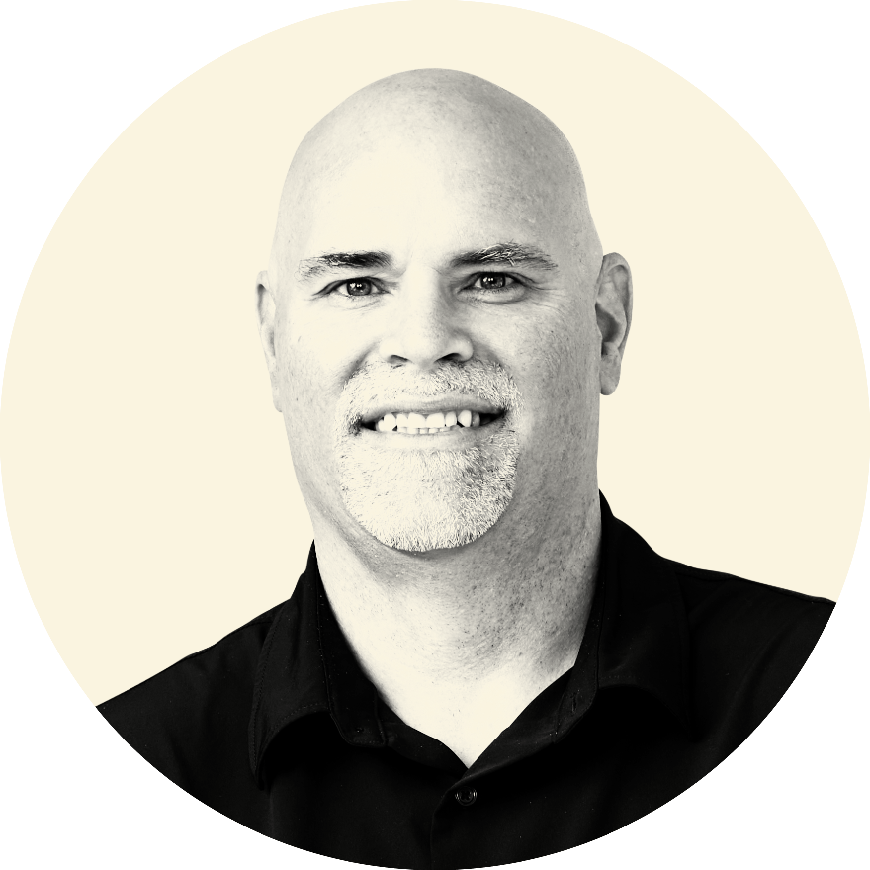 Black and white, professional portrait of a smiling, bald man wearing a black shirt against a light background.