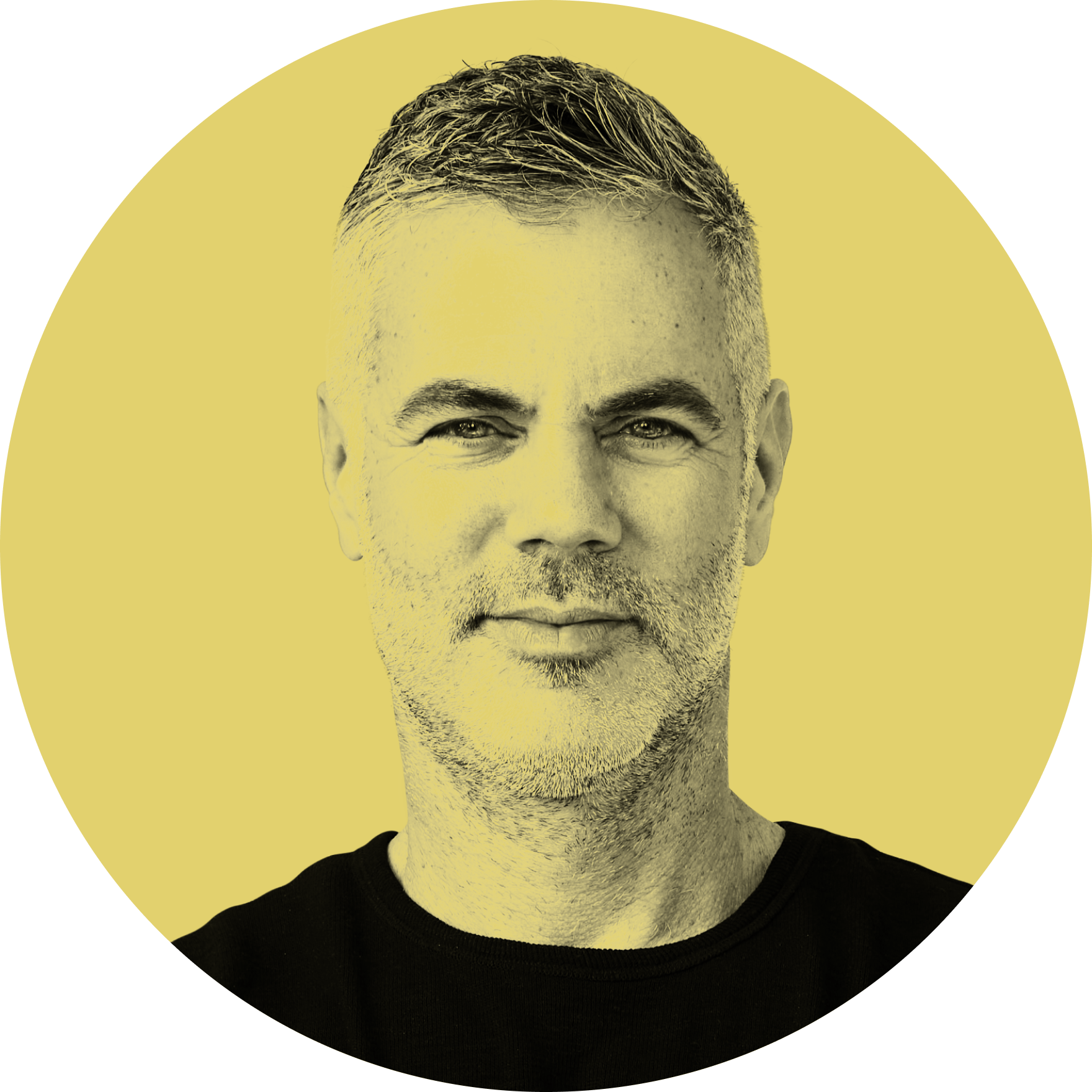 A close-up of a man with short, styled hair and a beard, wearing a black shirt, smiling softly against a yellow background.