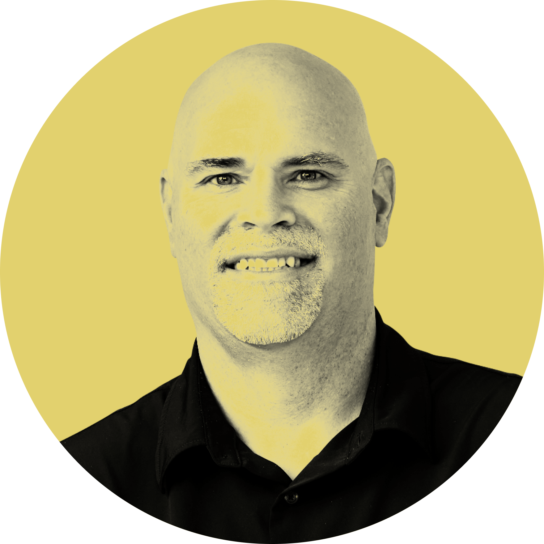 Black and white portrait of a smiling man with a shaved head and a goatee, wearing a dark shirt, with a yellow background.