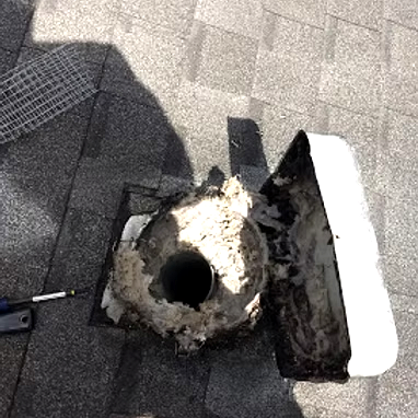 A bird bath with a broken part and a cover on a paved surface.