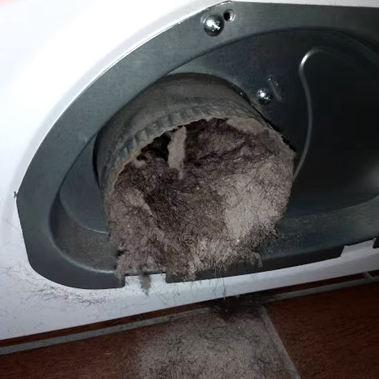LINT buildup inside the dryer vent with lint spilled outside.