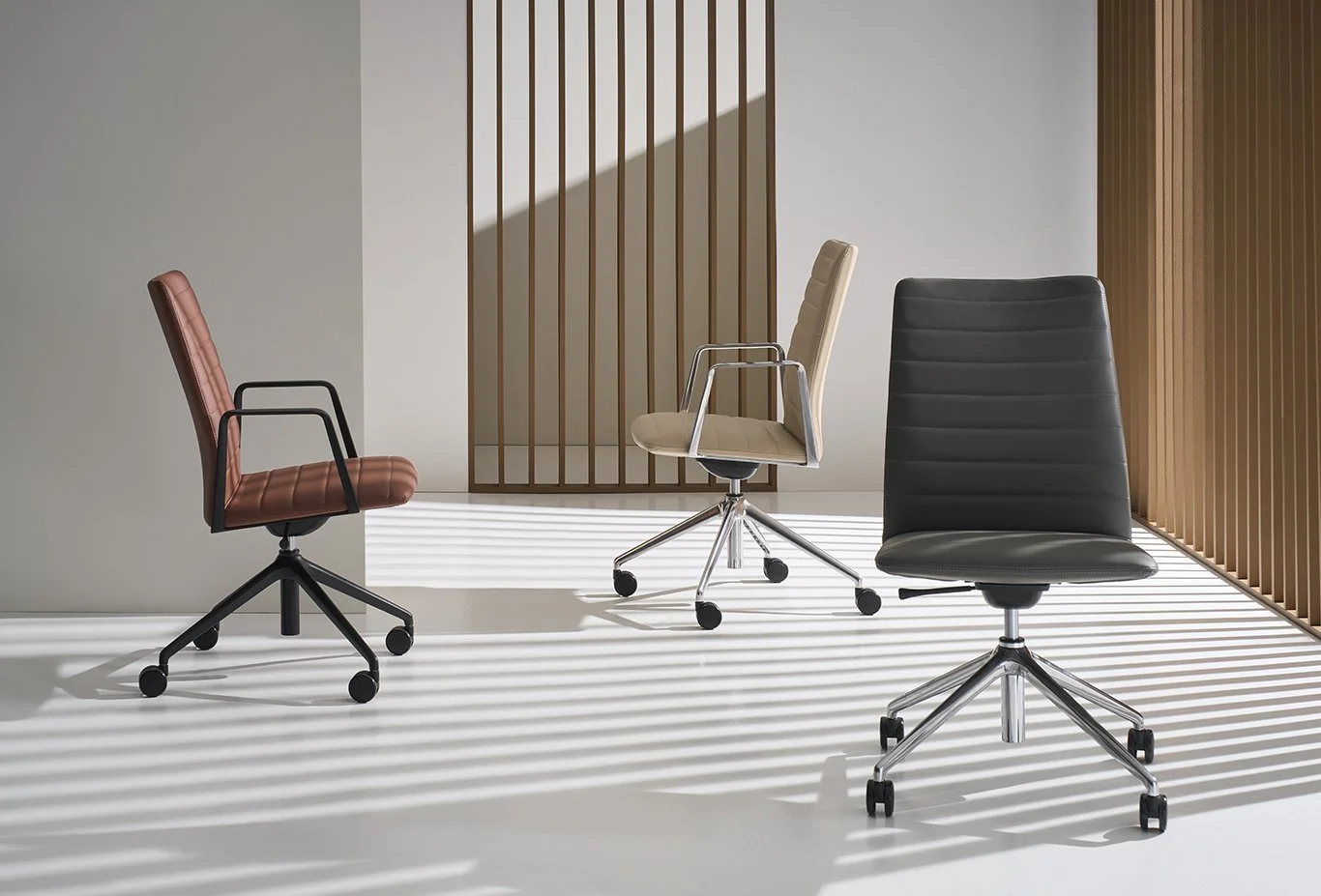 Three modern office chairs in a minimalist room with vertical wooden slats and shadow lines on the floor.