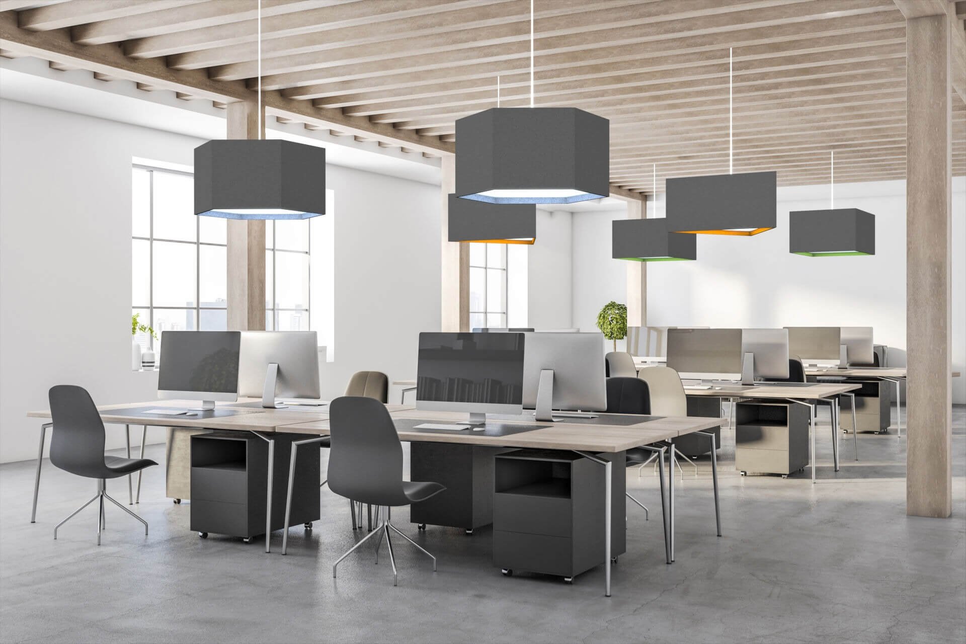 Modern open office space with rows of desks, desktop computers, gray chairs, large windows, and hexagonal pendant lights with colored edges hanging from a wooden ceiling.