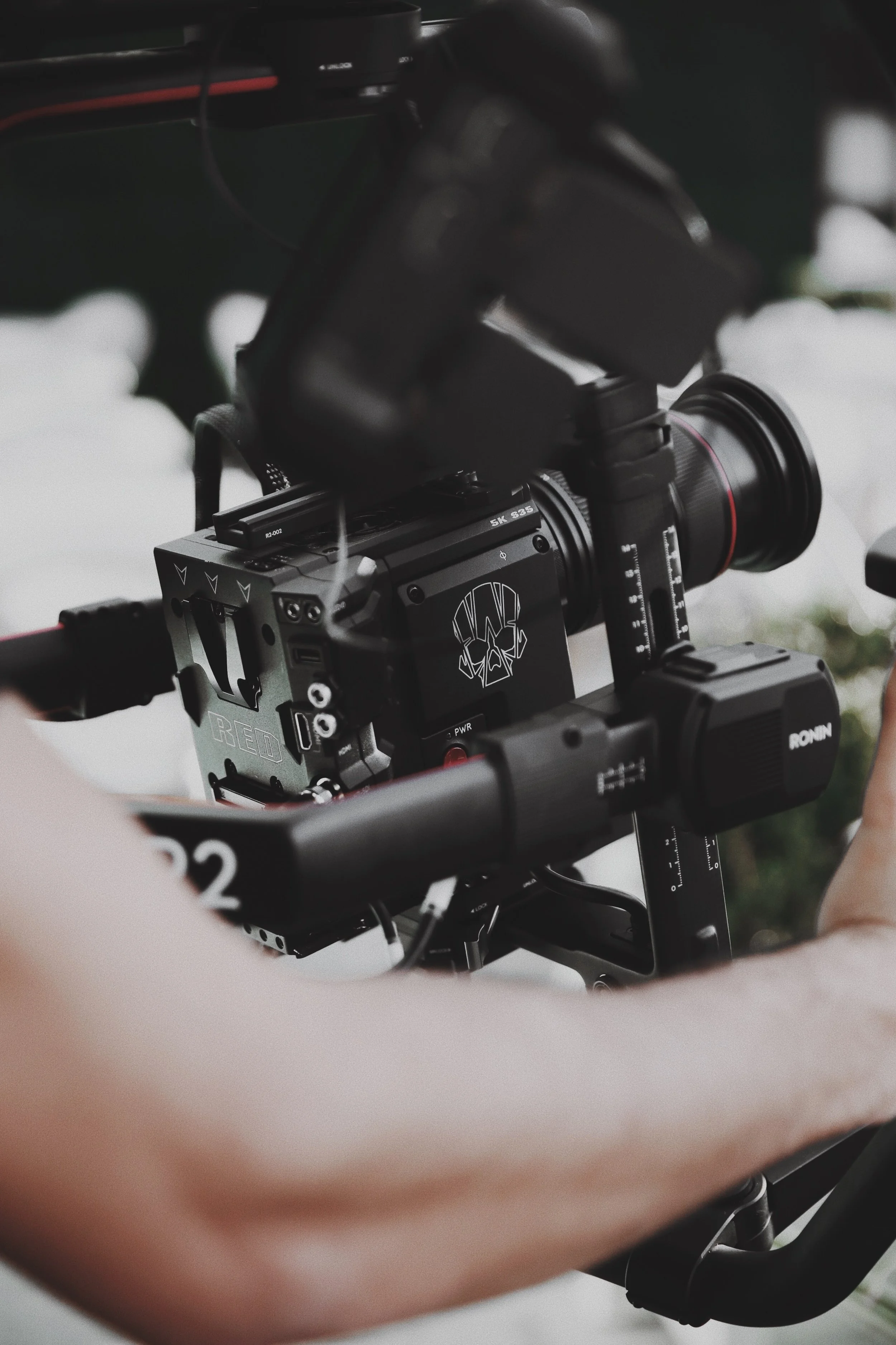 Close-up of a camera or filming equipment mounted on a stabilizer gimbal with a person's hand visible at the bottom.