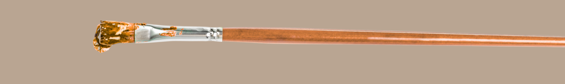 Close-up of paintbrush with brown paint on bristles