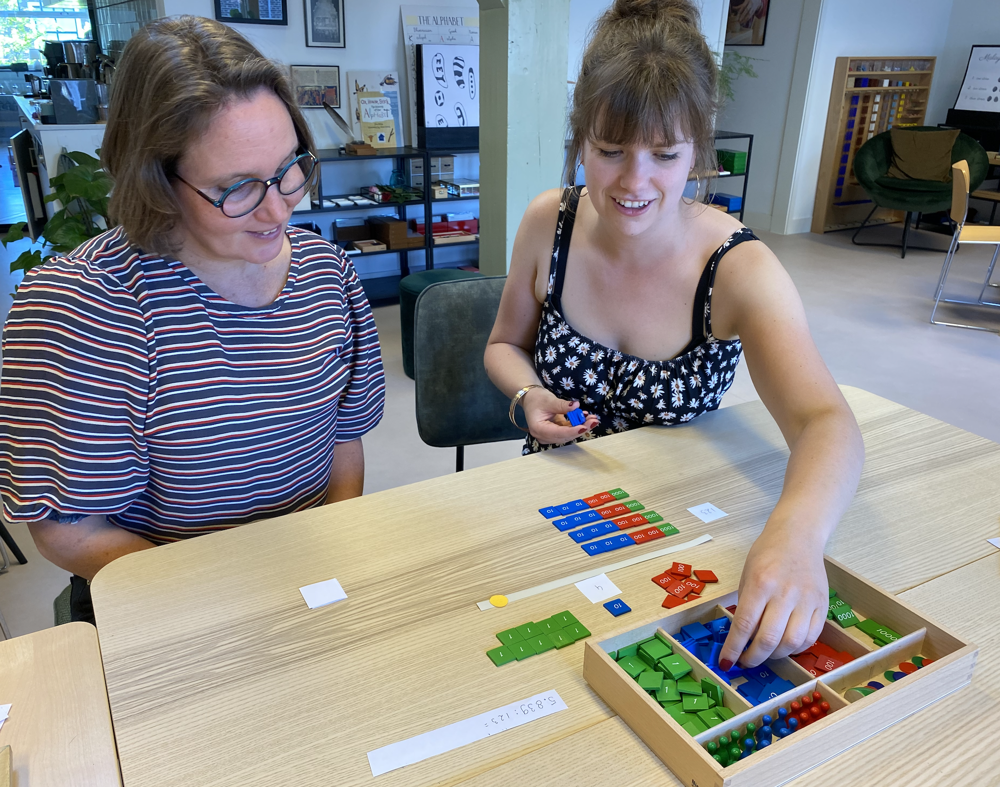 Two women practicing with Montessori material on the AMI 6-12 Diploma course in Delft at the International Montessori Institute (IMI).