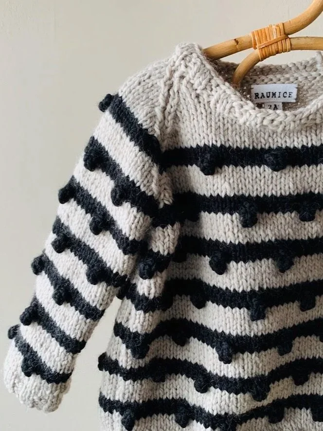 Navy and white Breton-stripe knitted jumper on a wooden hanger