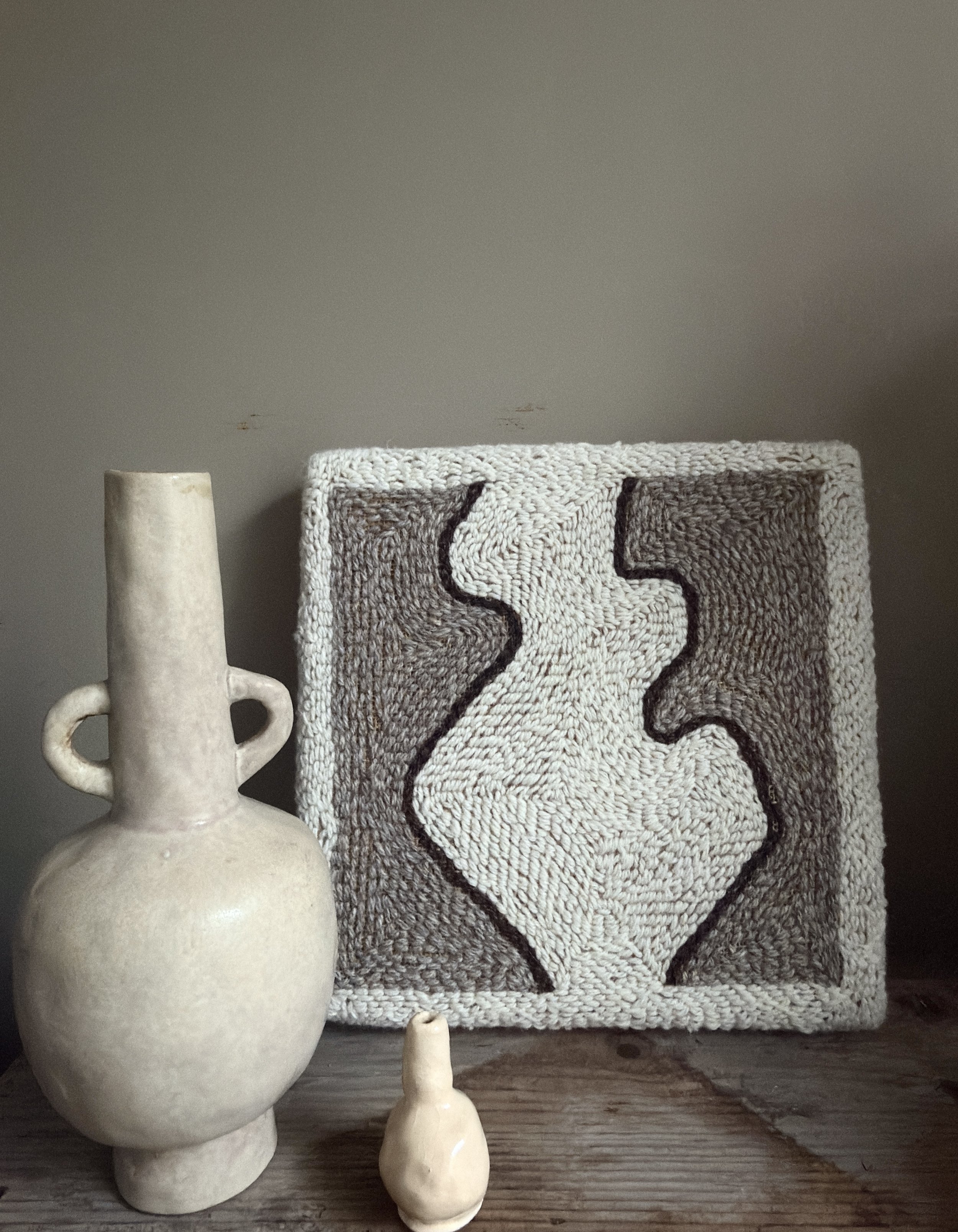 Small hand-punched Romney wool textile artwork displayed on a neutral wall in a contemporary interior
