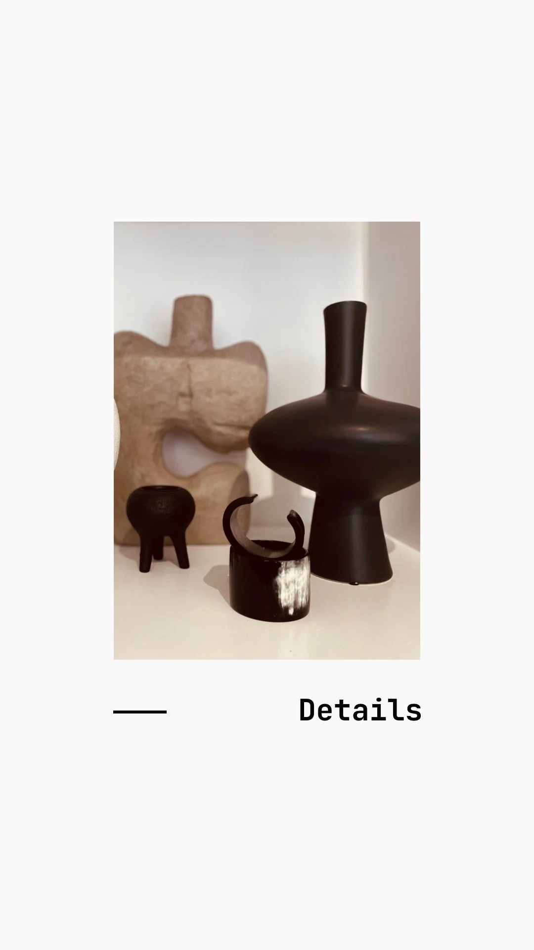 Various abstract black and beige ceramic sculptures on a white surface.