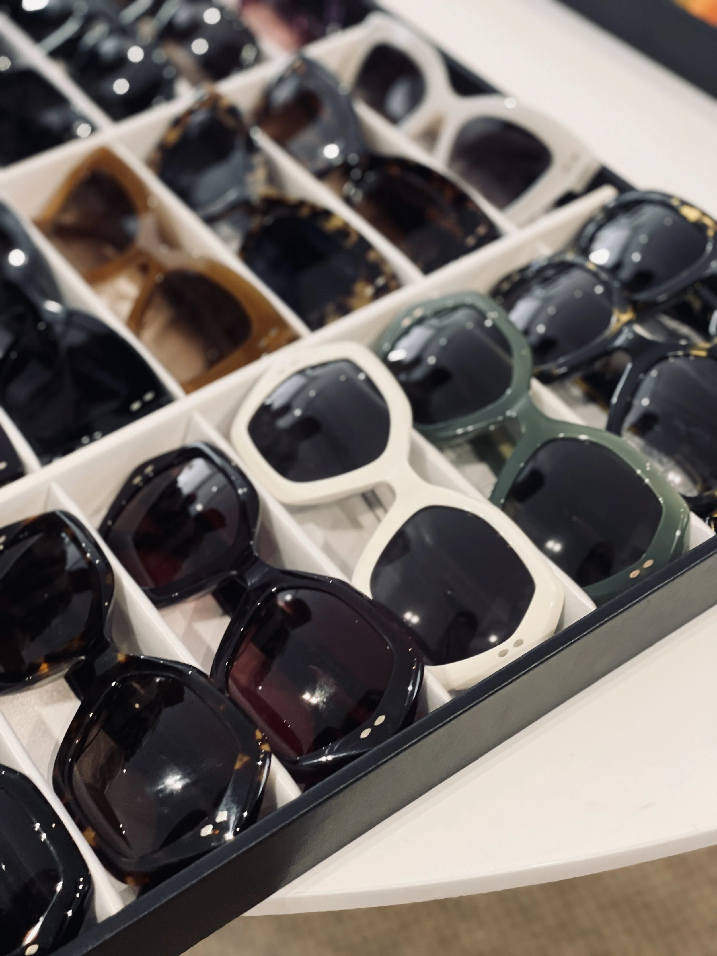 A display case of multiple pairs of sunglasses in various colors and styles.