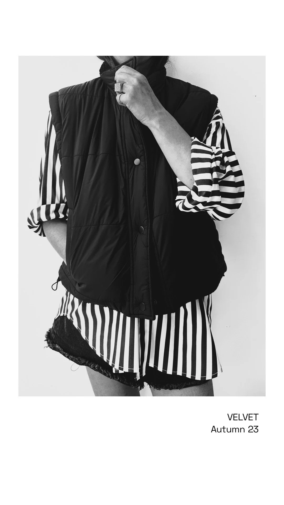 Black and white photo of a person wearing a striped shirt, a puffy vest, and frayed shorts, with text that reads 'VELVET Autumn 23'.