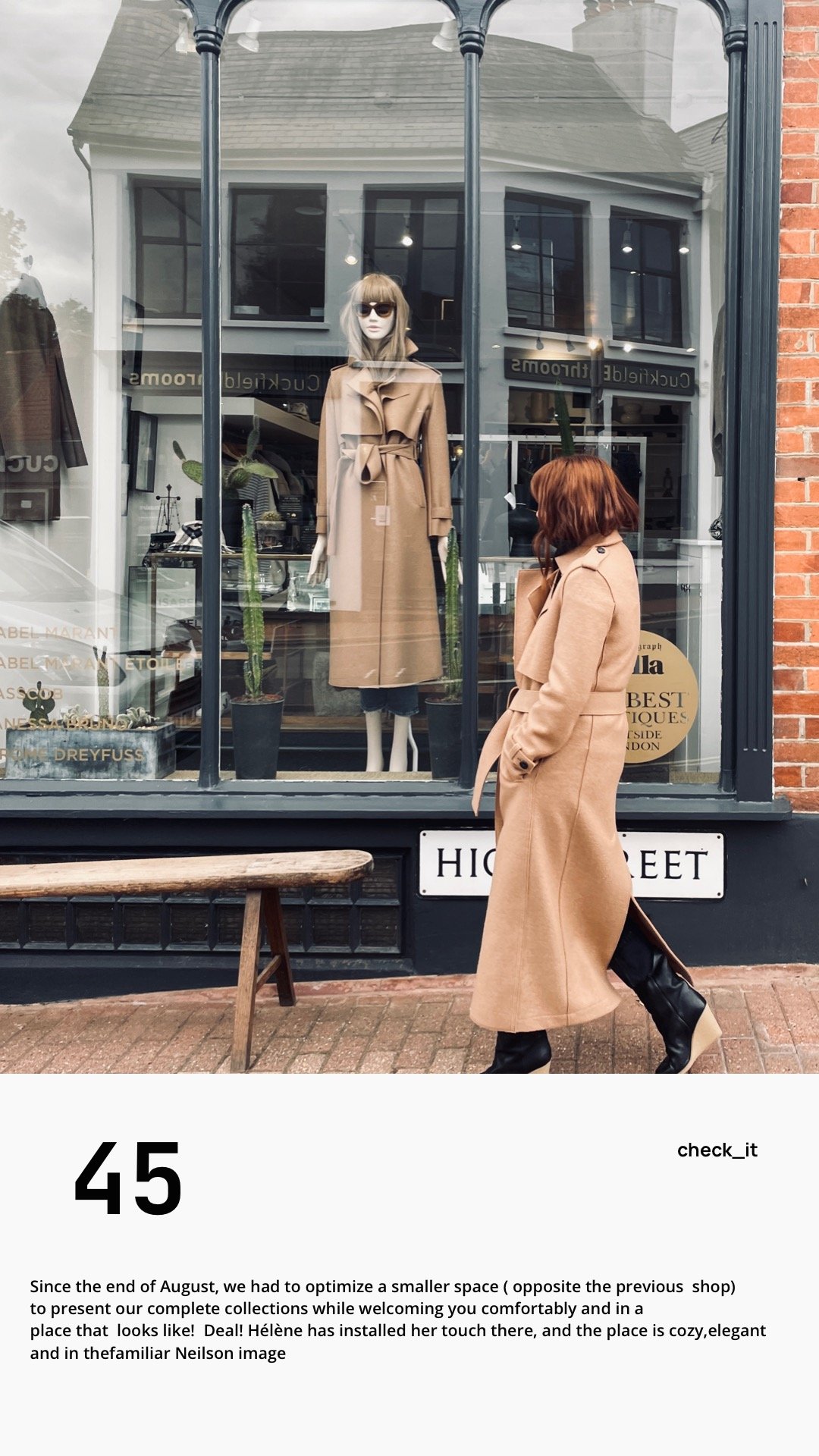 A woman with red hair and a tan coat standing outside a clothing store, looking at a mannequin dressed in a tan coat and sunglasses inside the shop window.