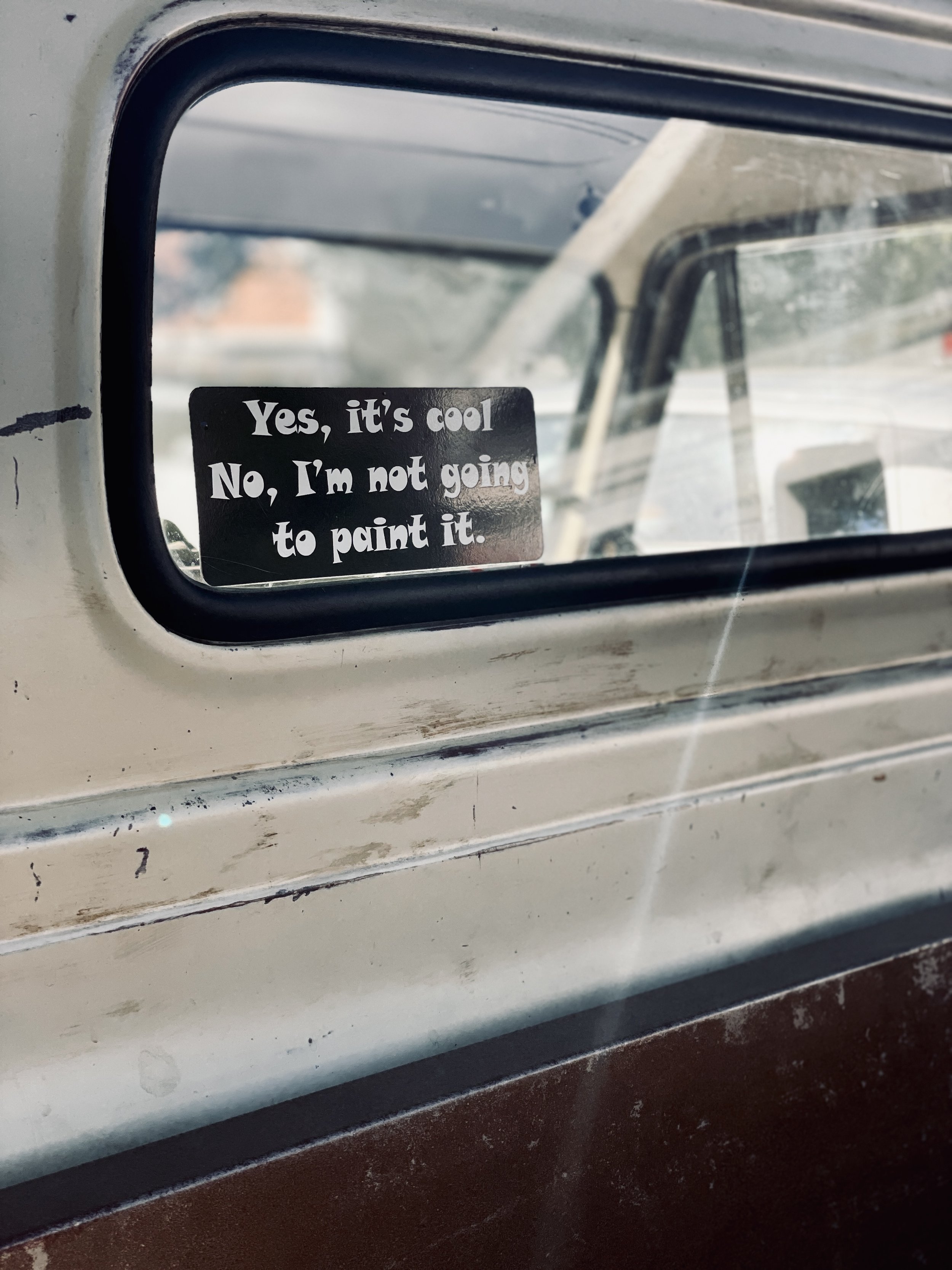 A sticker on a vintage car window with the text: 'Yes, it's cool. No, I'm not going to paint it.'