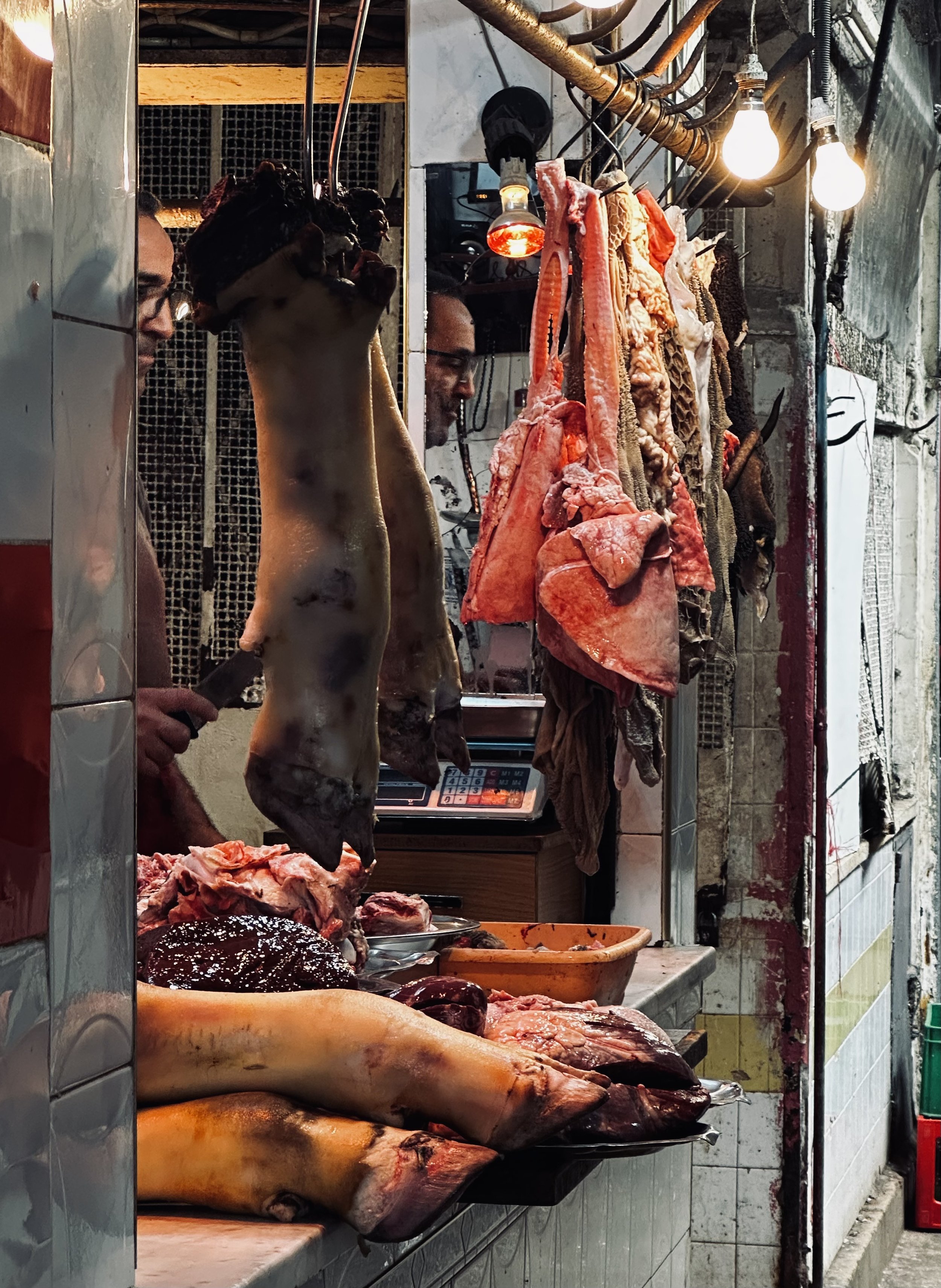Butcher shop with hanging animal carcasses and meat on the counter.