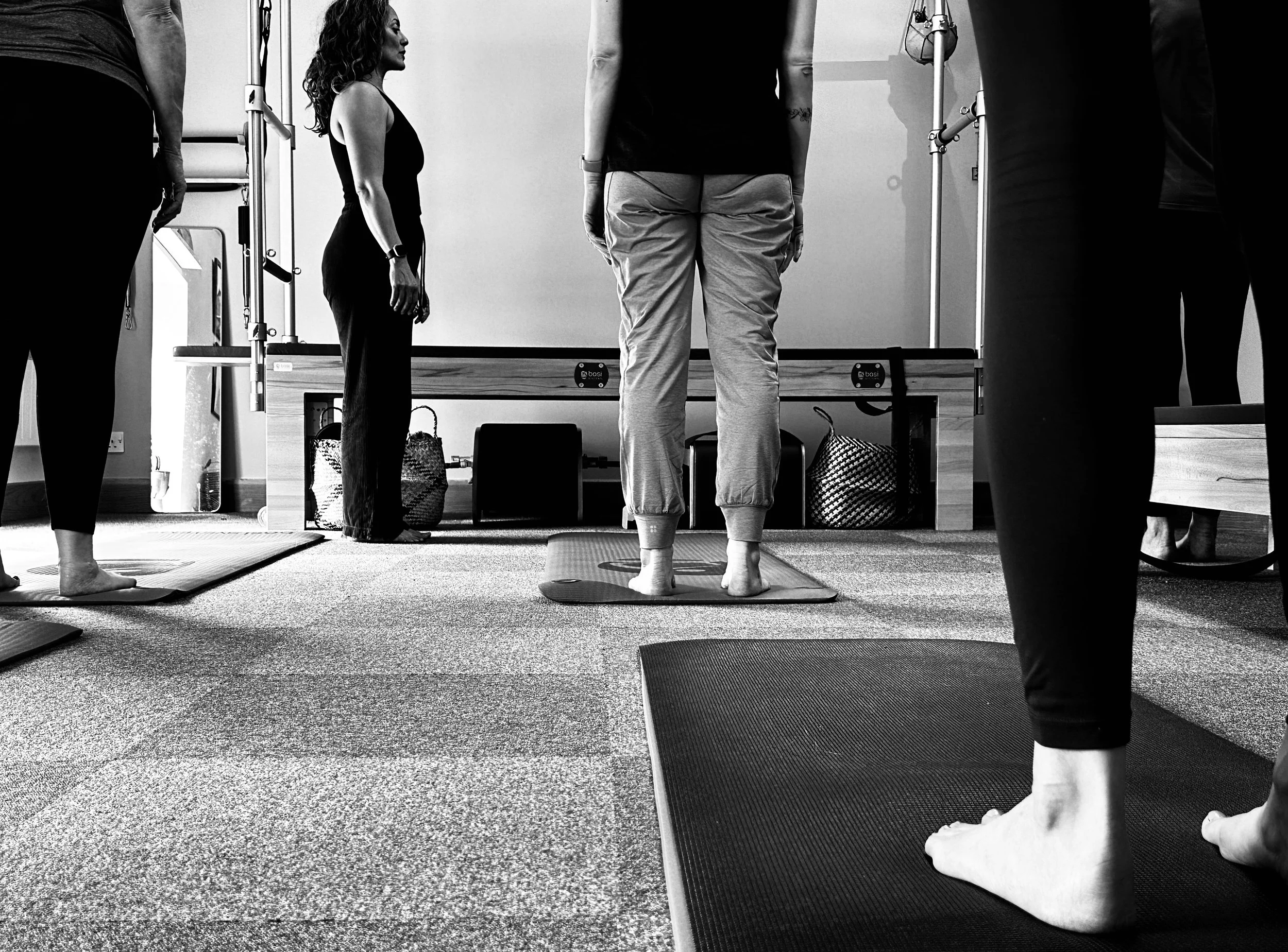 People participating in a yoga class or meditation session, standing on yoga mats in a room, with one instructor or leader at the front.