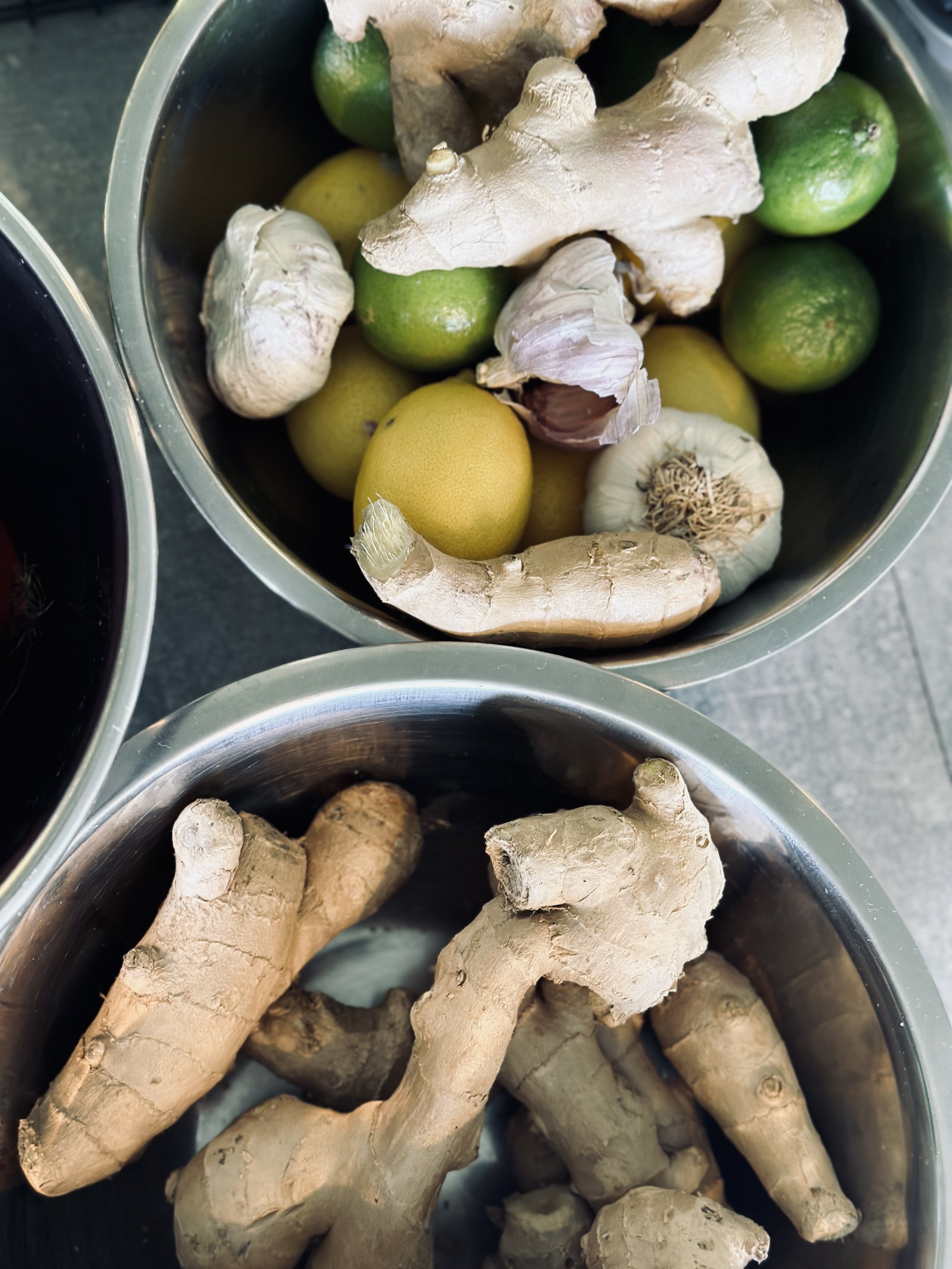 Baskets containing ginger, garlic, limes, and ginger root.