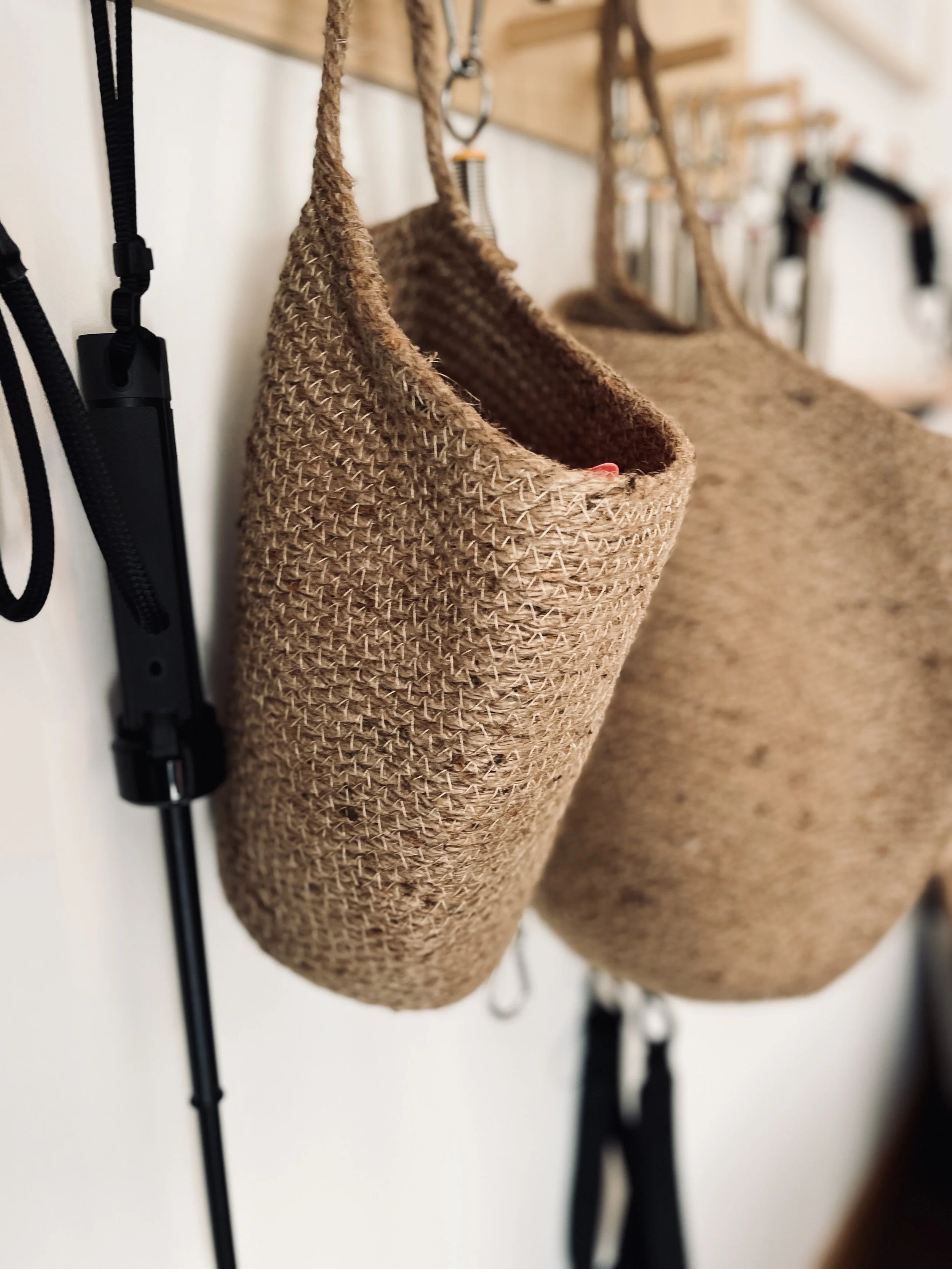 Two woven brown bags hanging on hooks, with various accessories hanging nearby.