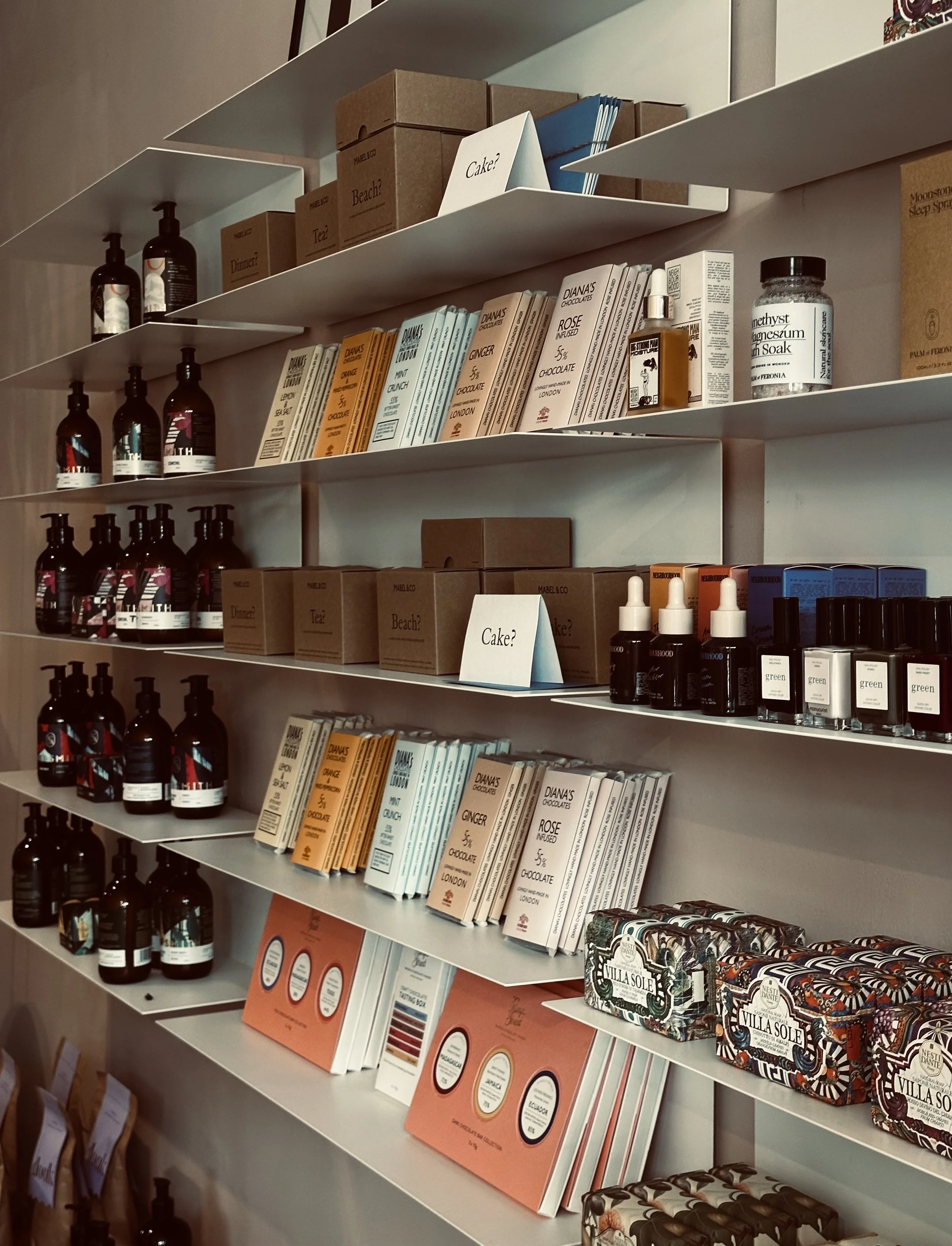 Shelves stocked with chocolate products, skincare items, and boxes with the signs 'Cake?' and 'Beach?' displayed.