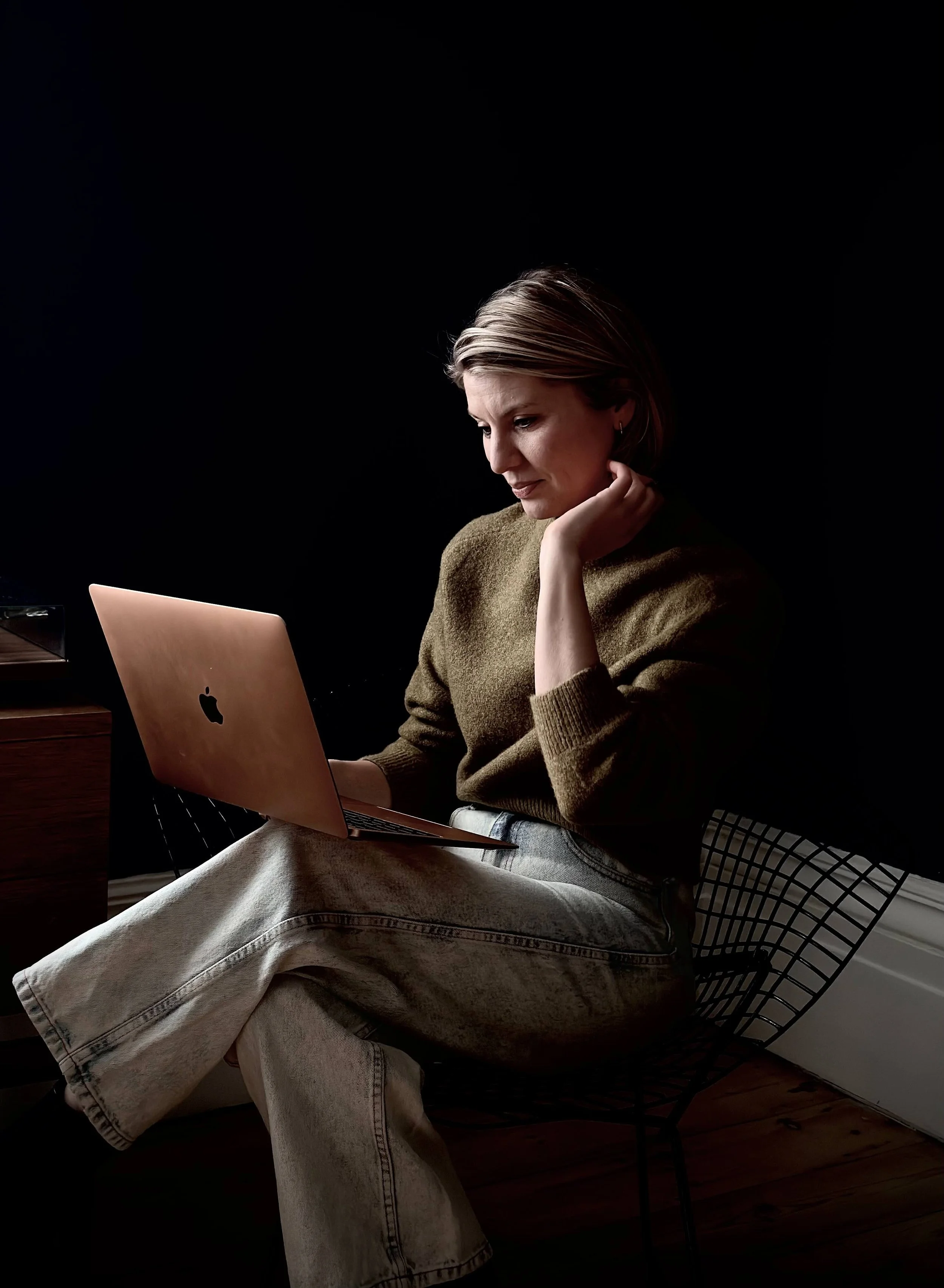 woman looking at her laptop, sitting on a chair