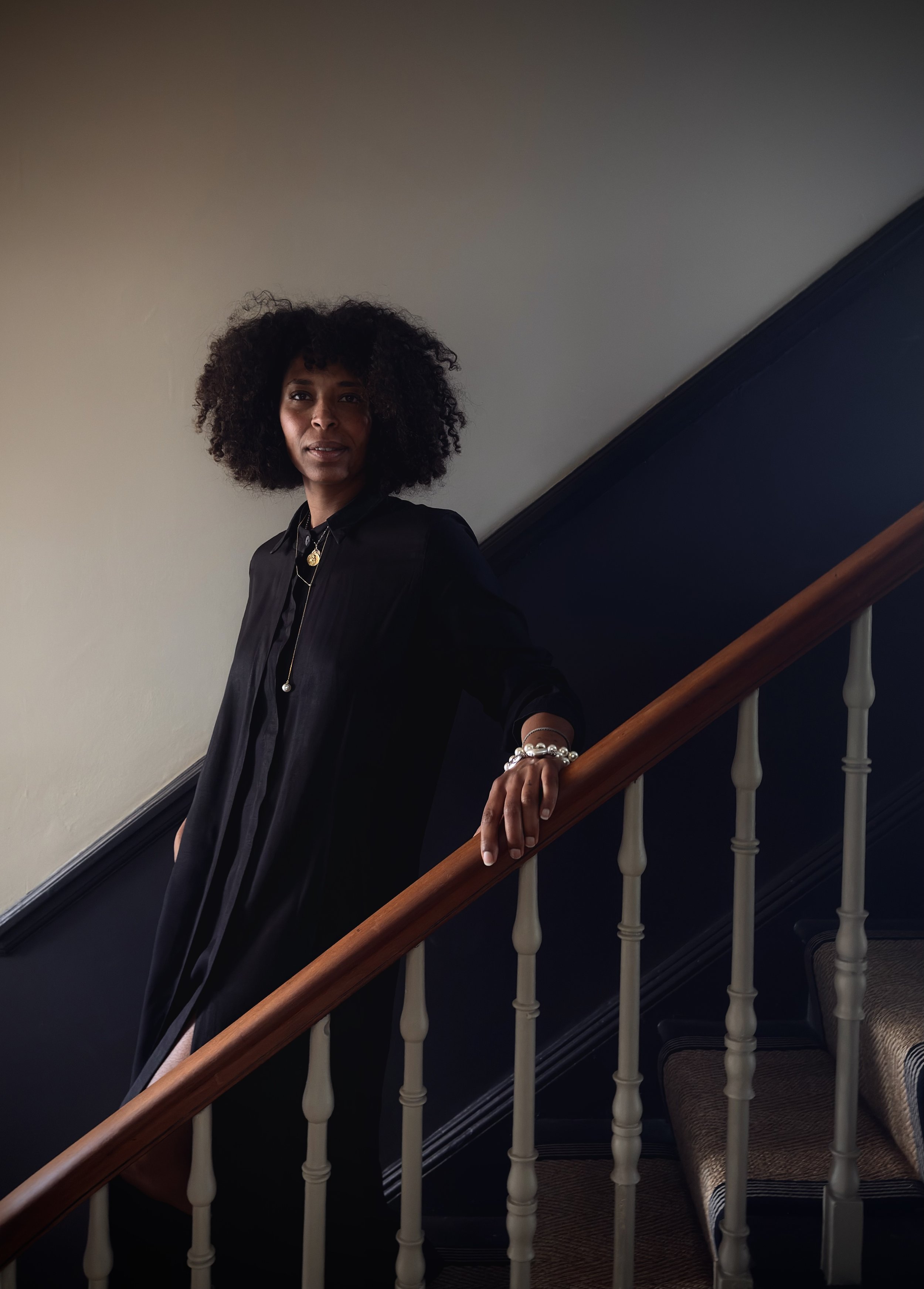 woman standing in the stairs with one hand on the banister 