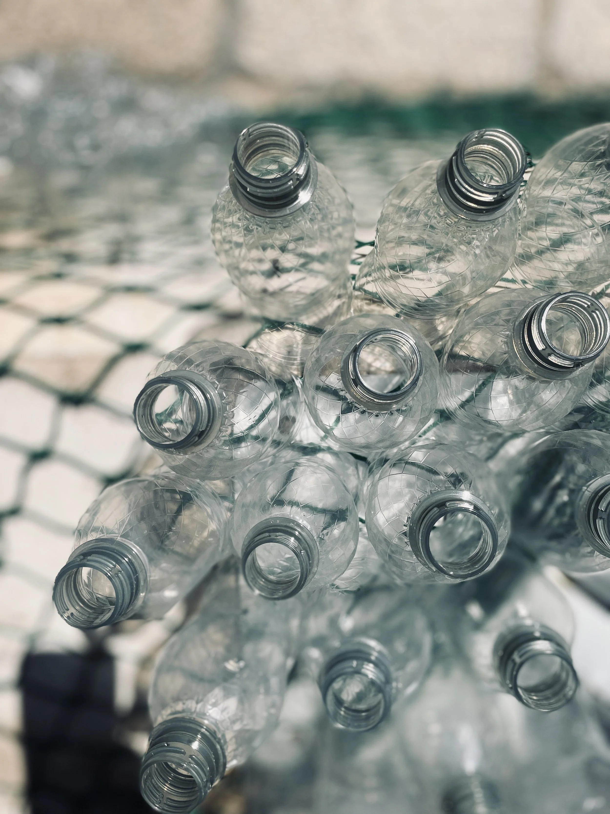 Close-up of empty plastic water bottles stacked on a wire mesh surface.