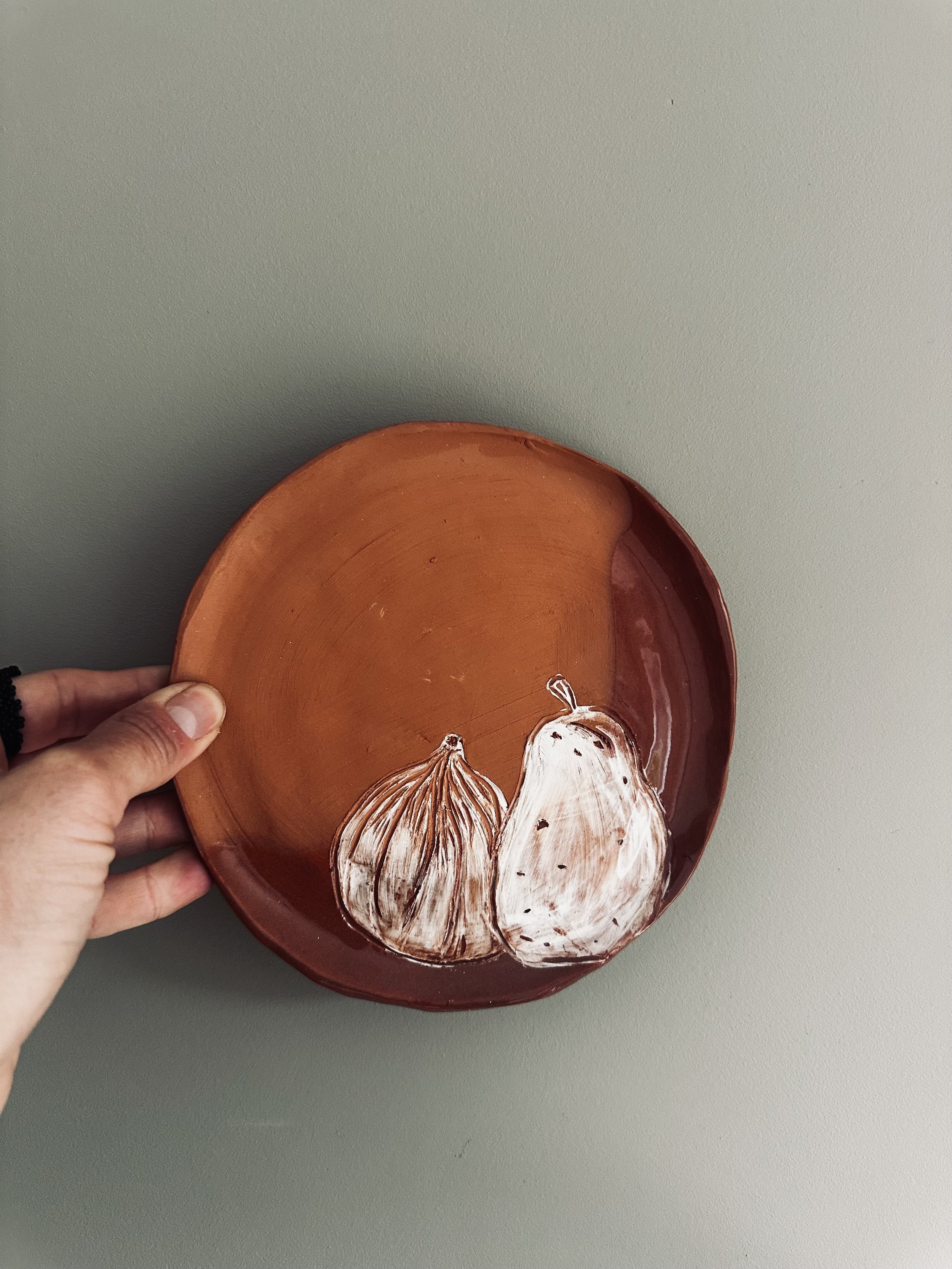 Hand holding a ceramic bowl with painted onions on the inside surface.