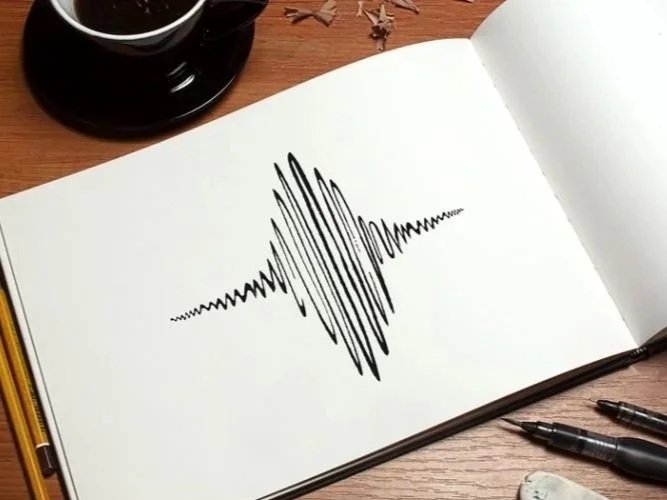 Open sketchbook with a drawing of a sound wave on a wooden desk, with a coffee mug and pens nearby.