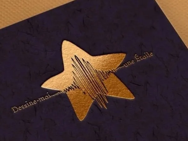 Close-up of a dark blue textured card with a gold star cutout and gold text underneath.