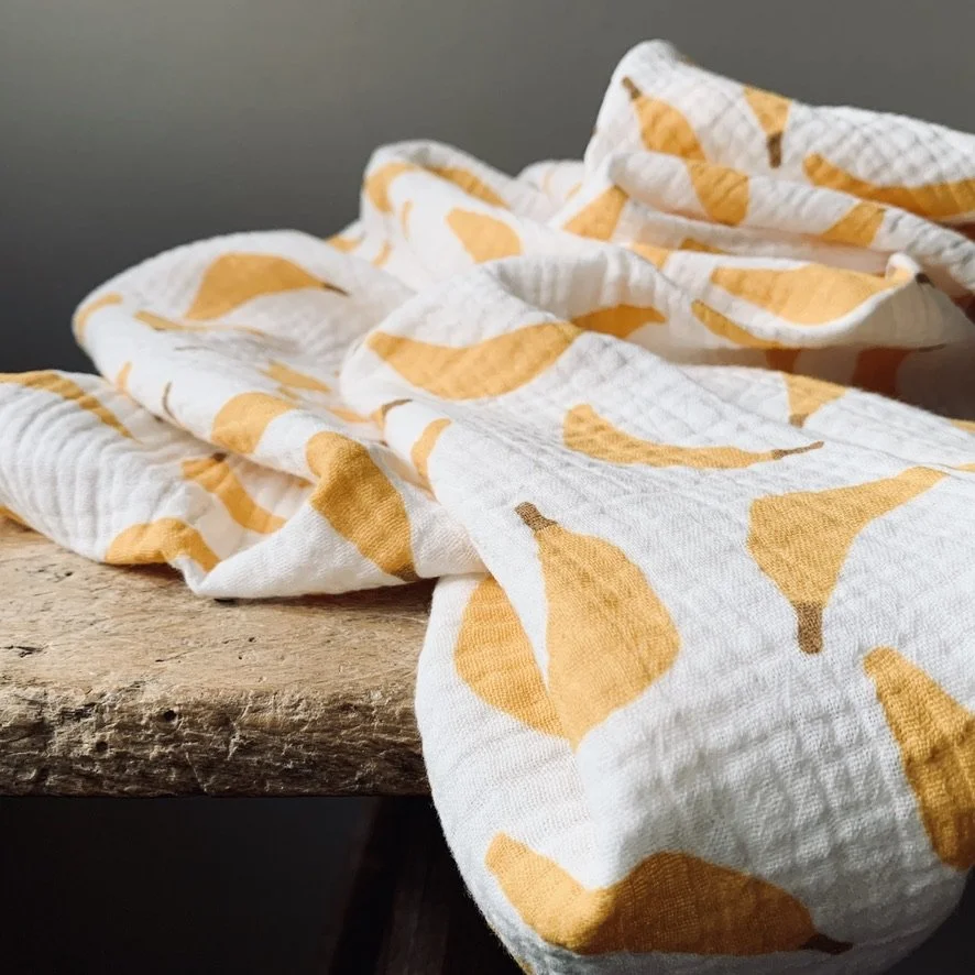A white kitchen towel with an orange pattern laid on a rustic wooden surface.
