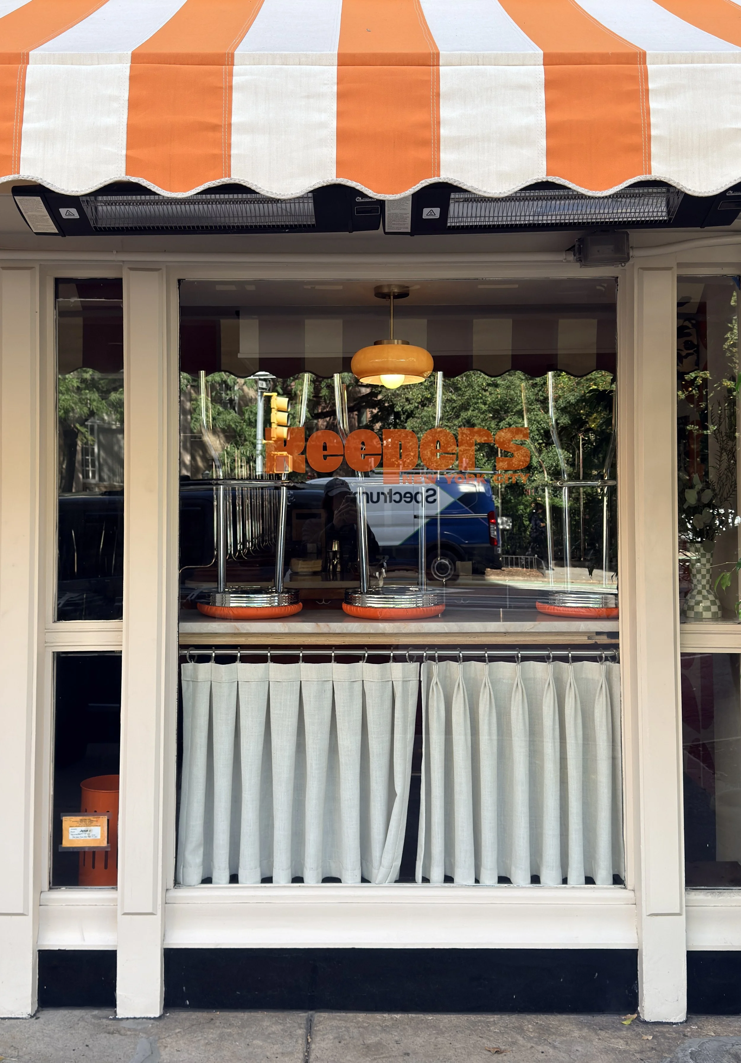 Orange-and-white striped awning above a café window with retro orange lettering, New York