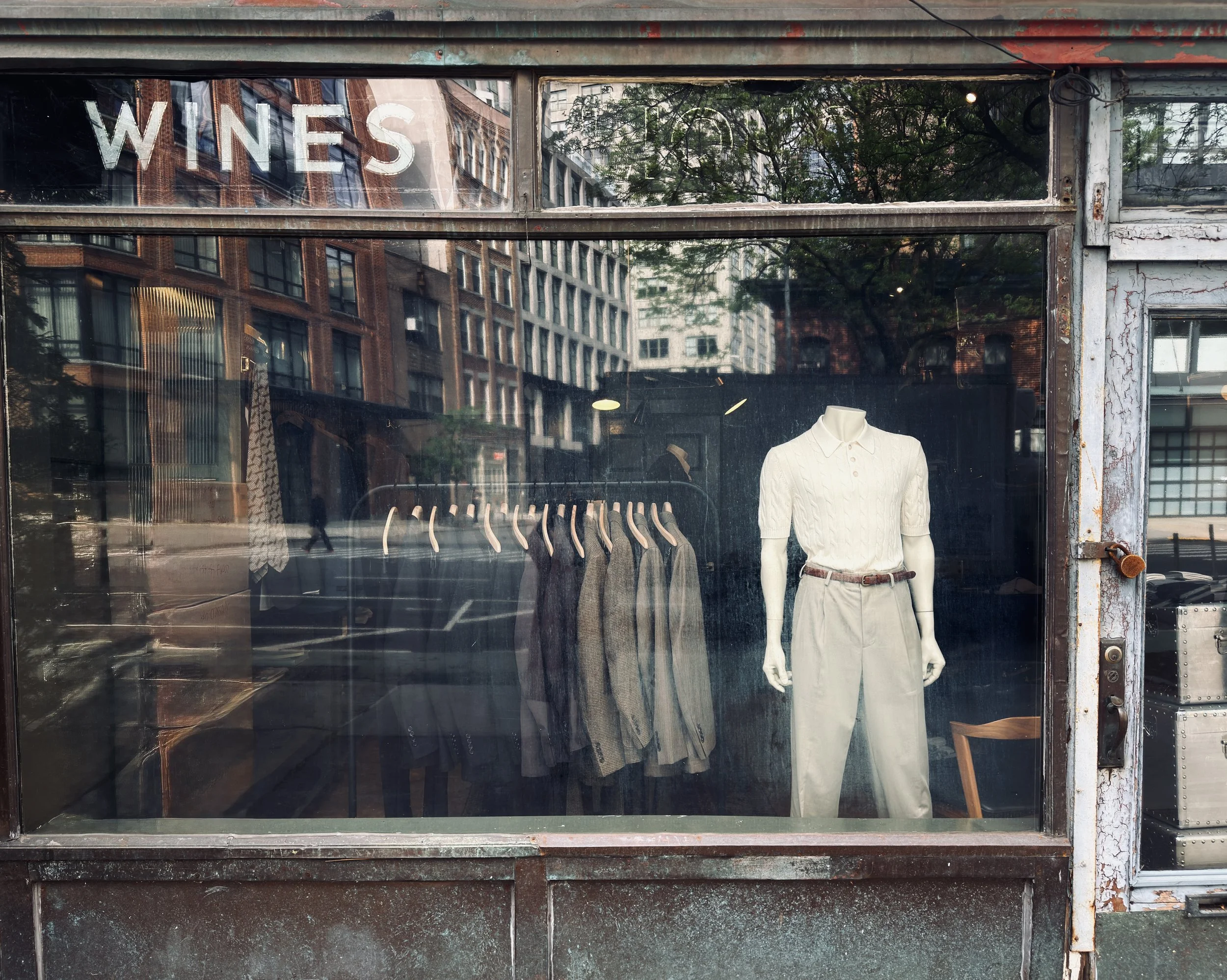 "Wines" lettering on a shop window displaying a mannequin and menswear, New York