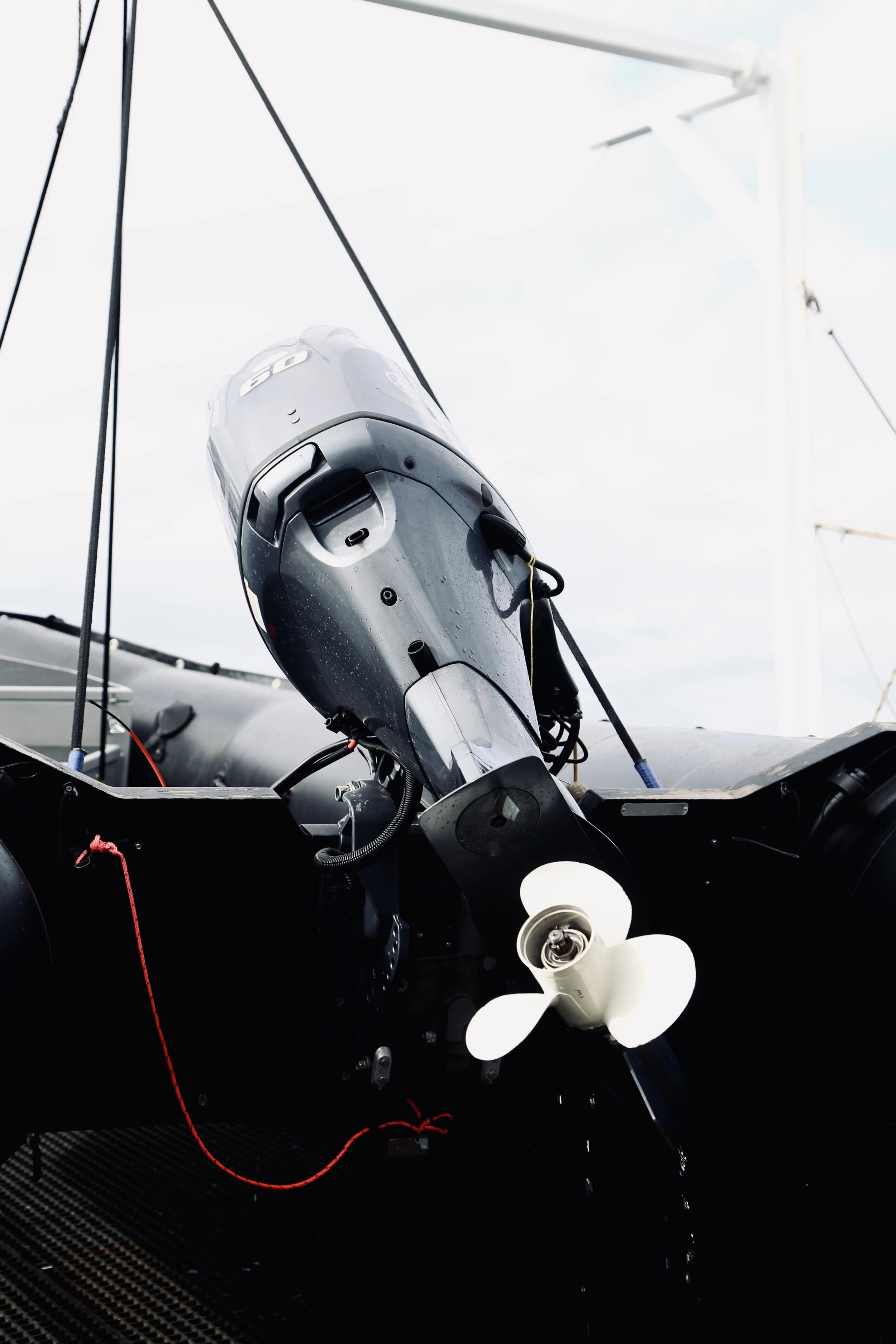 Close-up of a boat's outboard motor with a white propeller, mounted on the stern, with the boat's black hull visible.