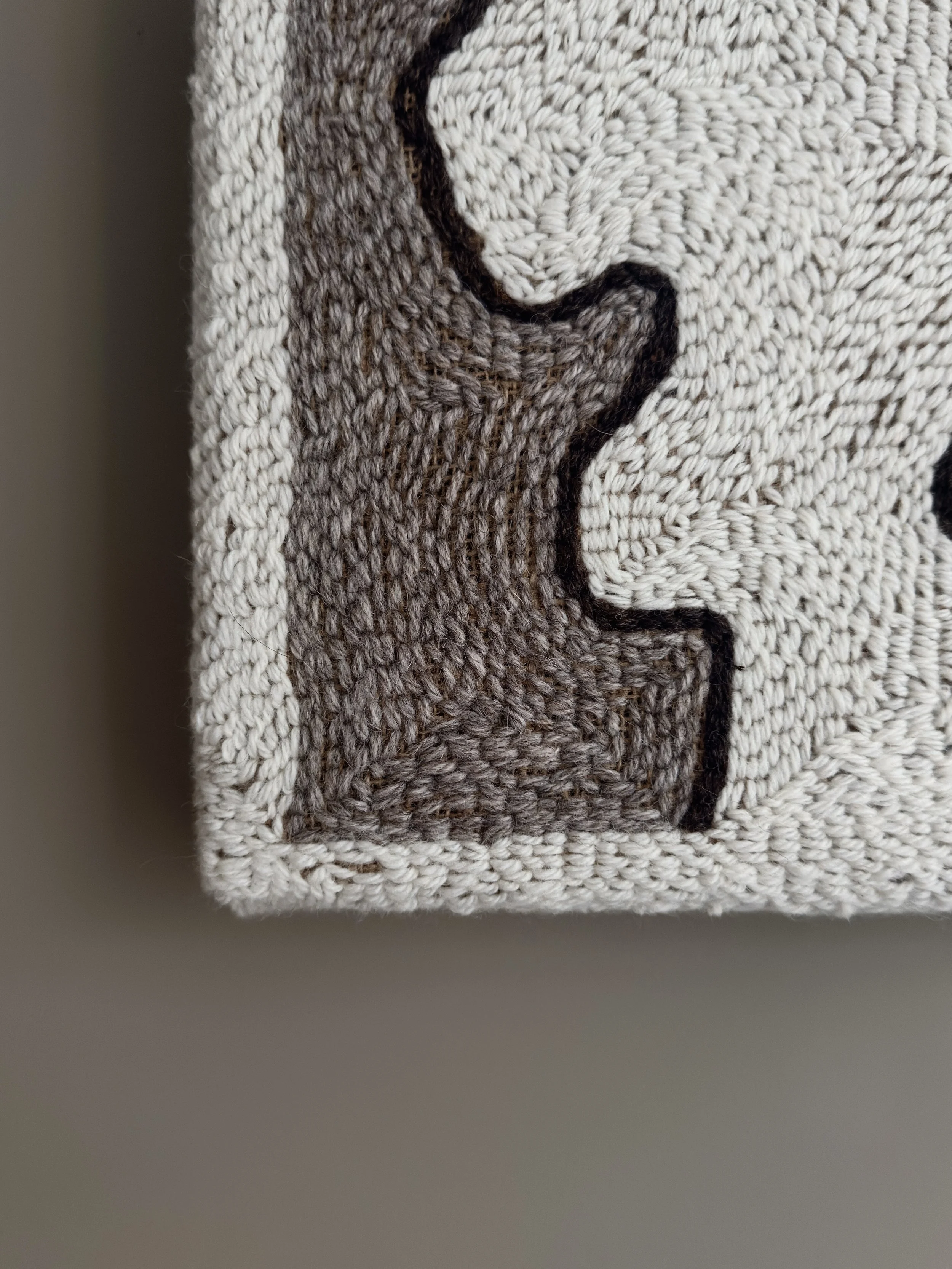 Close-up of hand-punched Romney yarn loops revealing the textured surface and natural hessian backing