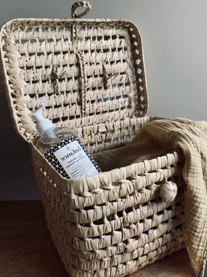 Open wicker basket holding a glass bottle, styled on a neutral background