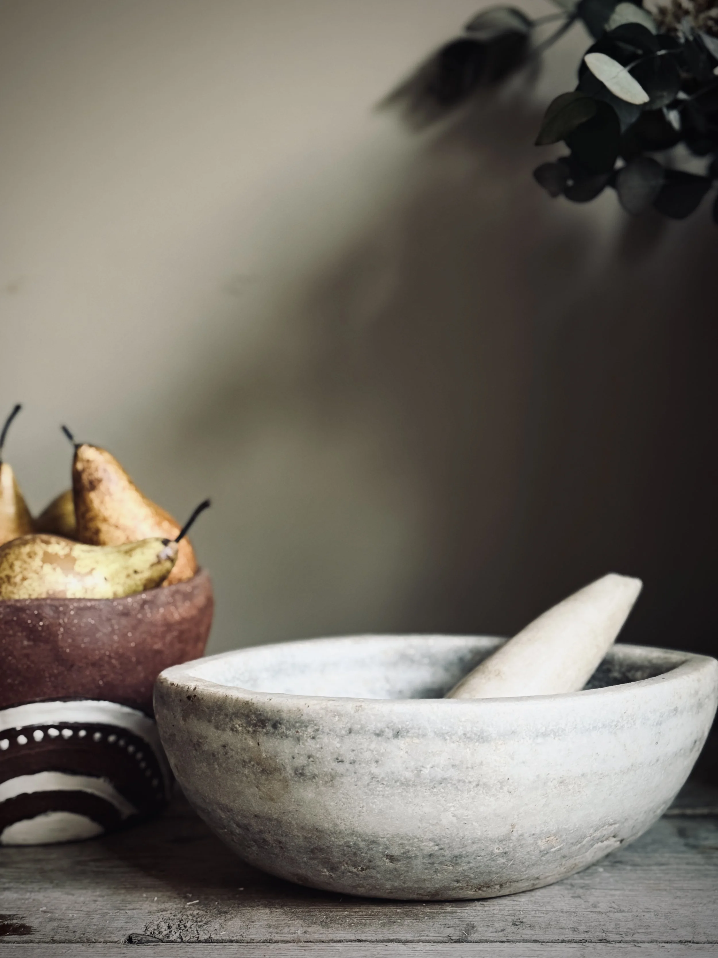 Stone mortar and bowl styled with pears and foliage, curated artisanal objects in The MUSE Shop Brighton